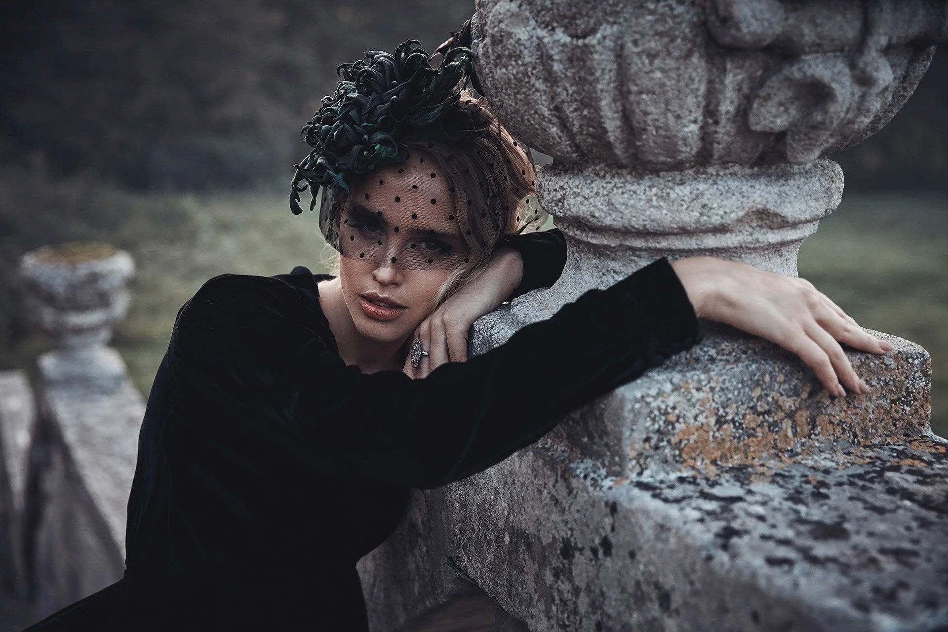 Femme_en_robe_noire_avec_un_voile_près_d’une_balustrade_en_pierre.jpeg