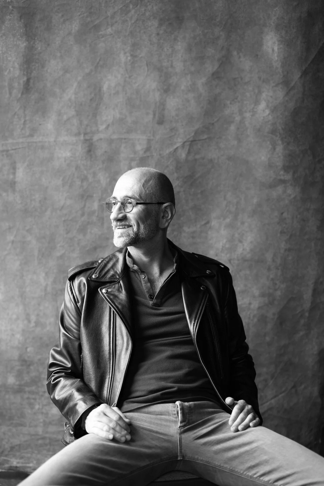 Man_in_leather_jacket_seated_against_textured_backdrop.jpeg