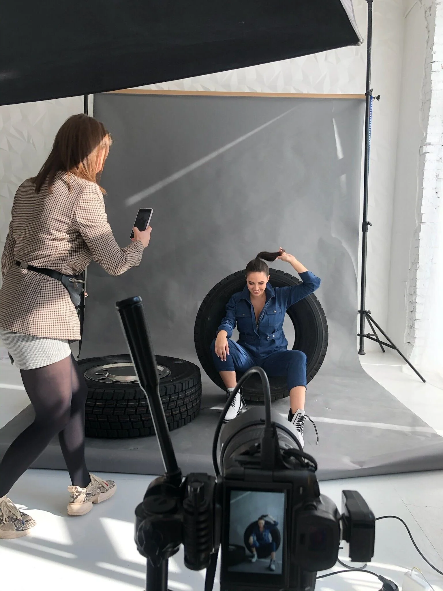 Model_in_denim_jumpsuit_posing_with_tires_in_studio.jpeg