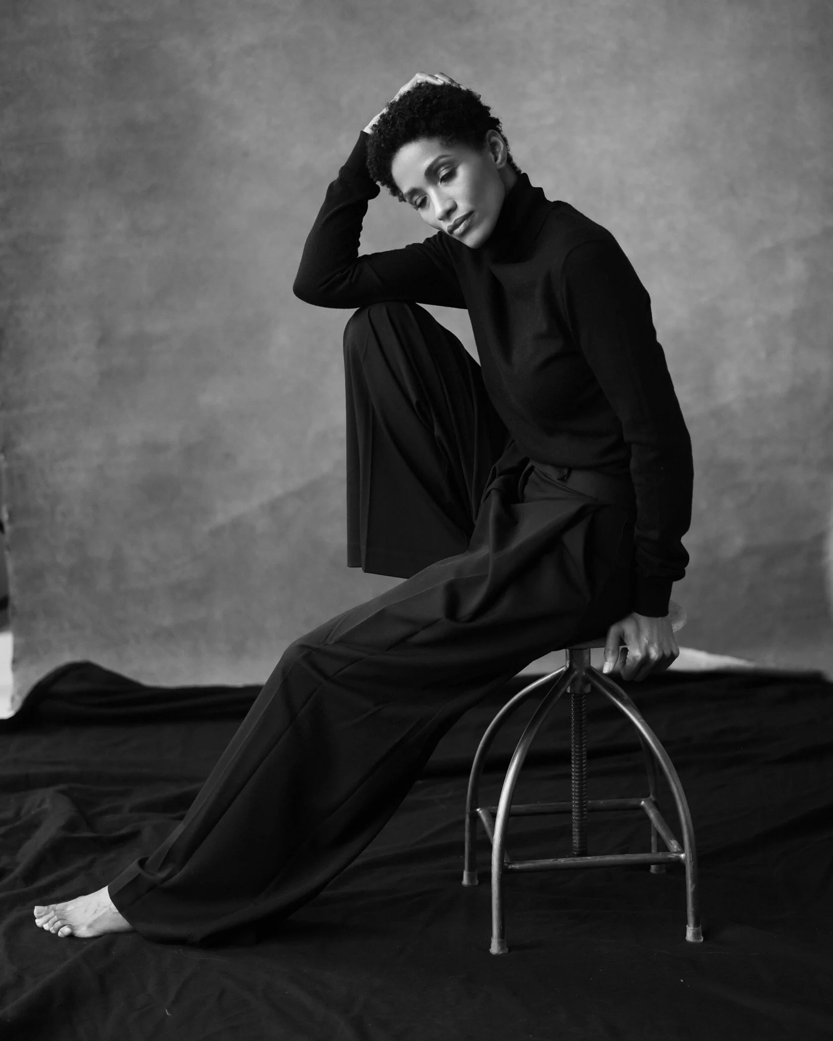 Woman_in_Black_Turtleneck_and_Trousers_Posing_on_Stool.jpg