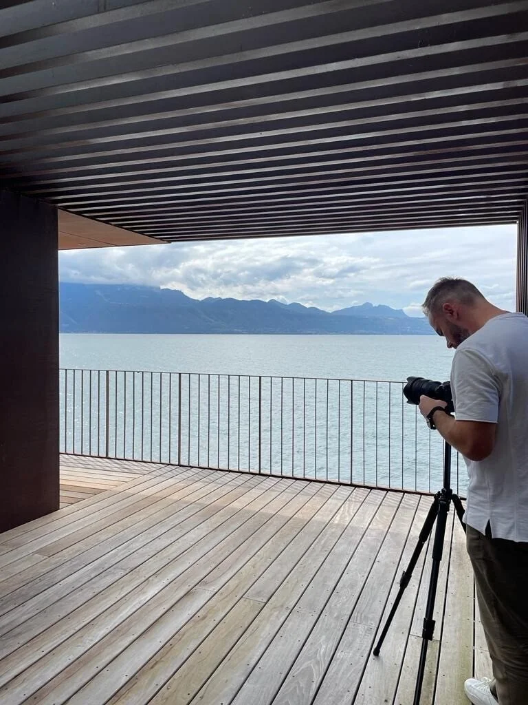 Photographer_on_wooden_deck_overlooking_lake_and_mountains.jpg
