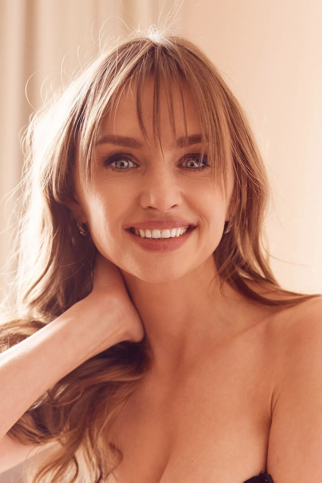 Smiling_woman_with_long_hair_in_soft_lighting.jpg