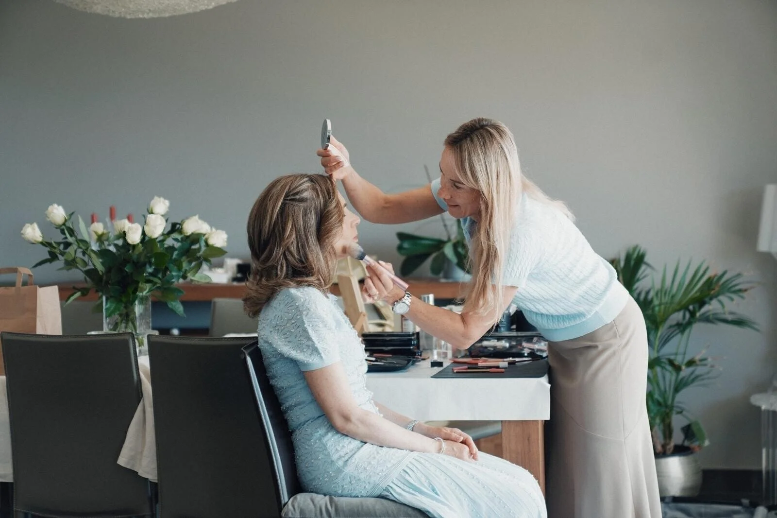 Woman_in_light_blue_dress_receiving_makeup_in_modern_setting.jpg