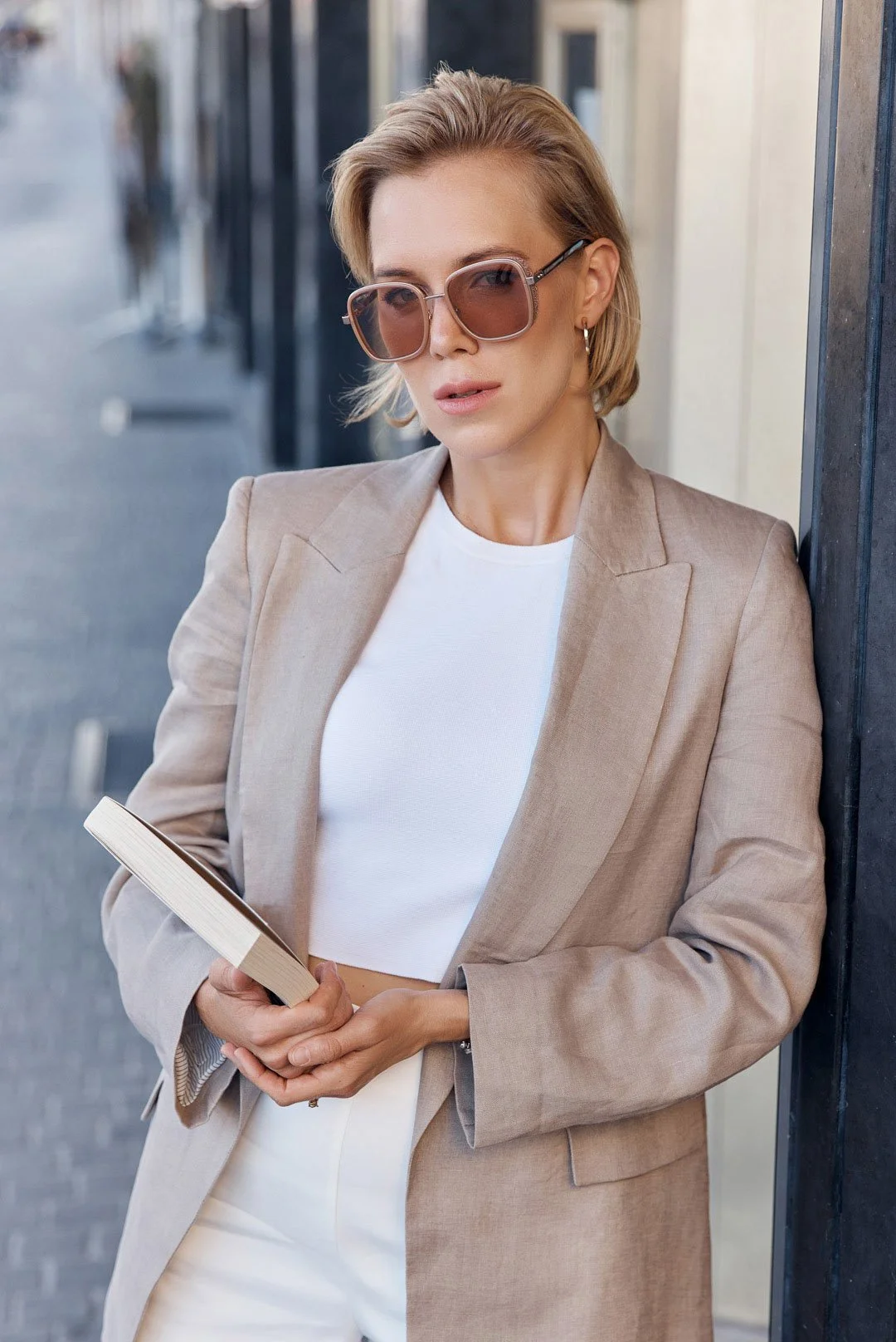 Woman_in_beige_blazer_holding_a_book_outdoors.jpg