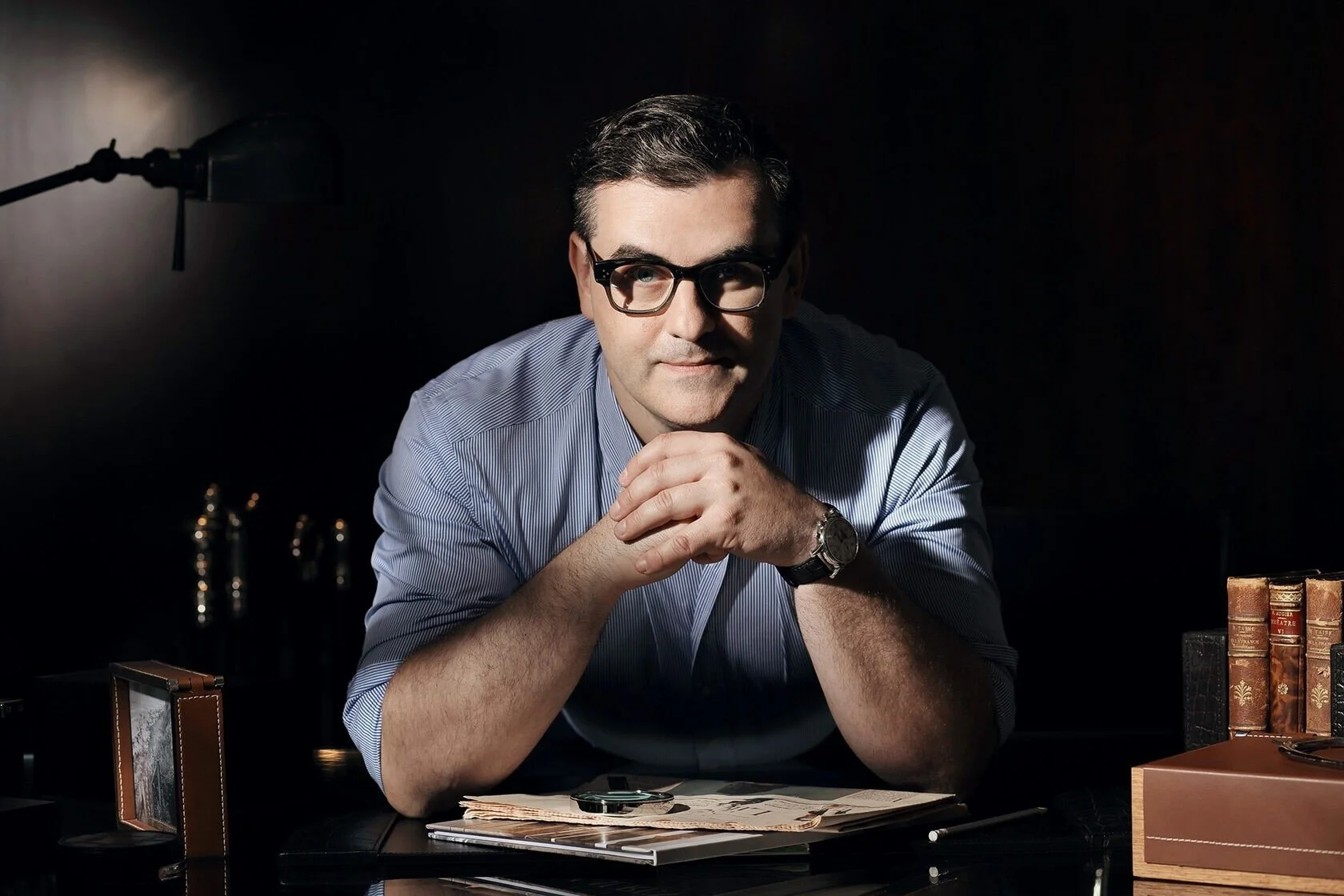 Man_in_blue_shirt_with_glasses_at_desk_with_documents.jpeg