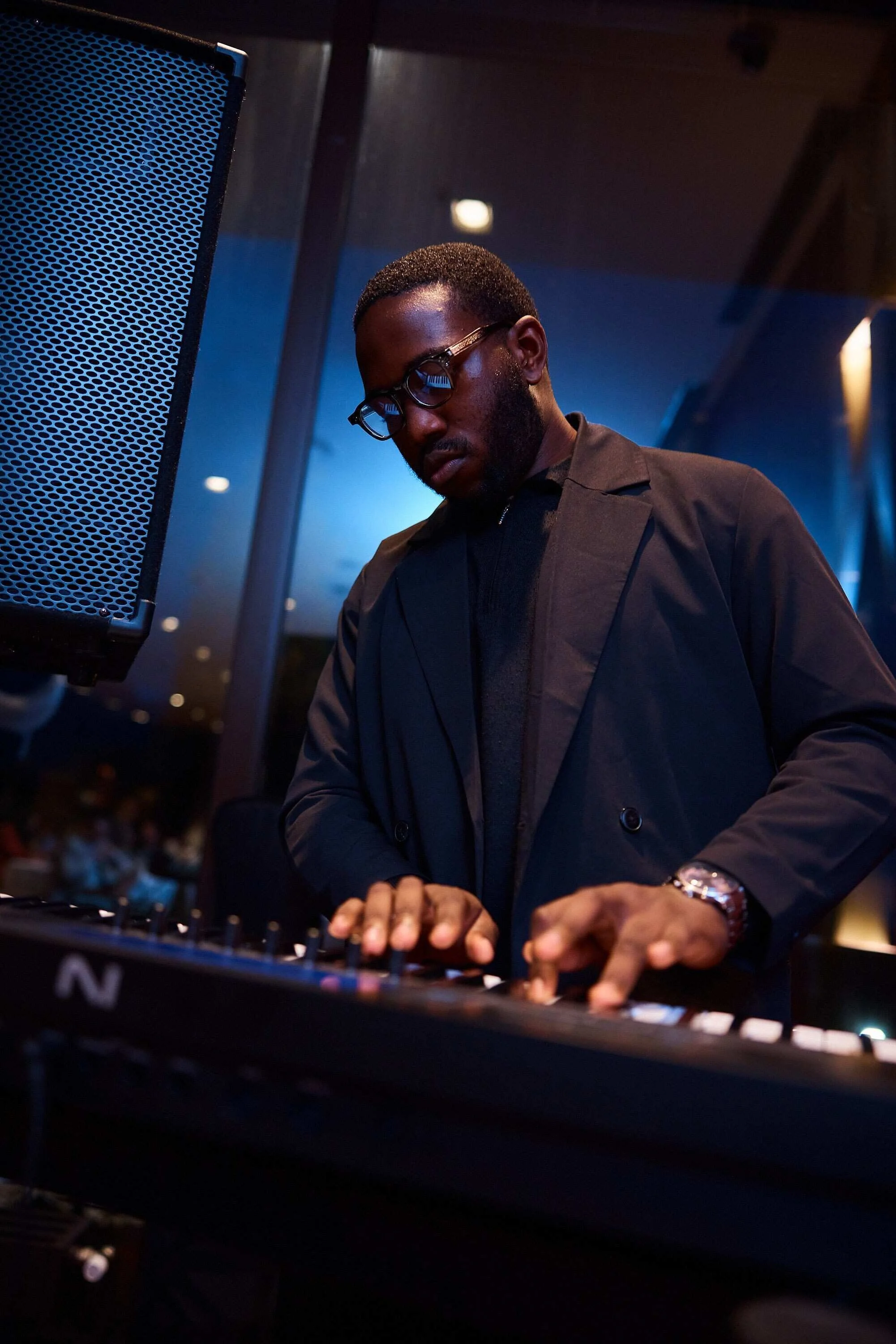 Man_in_black_jacket_playing_keyboard_in_dimly_lit_venue.jpg