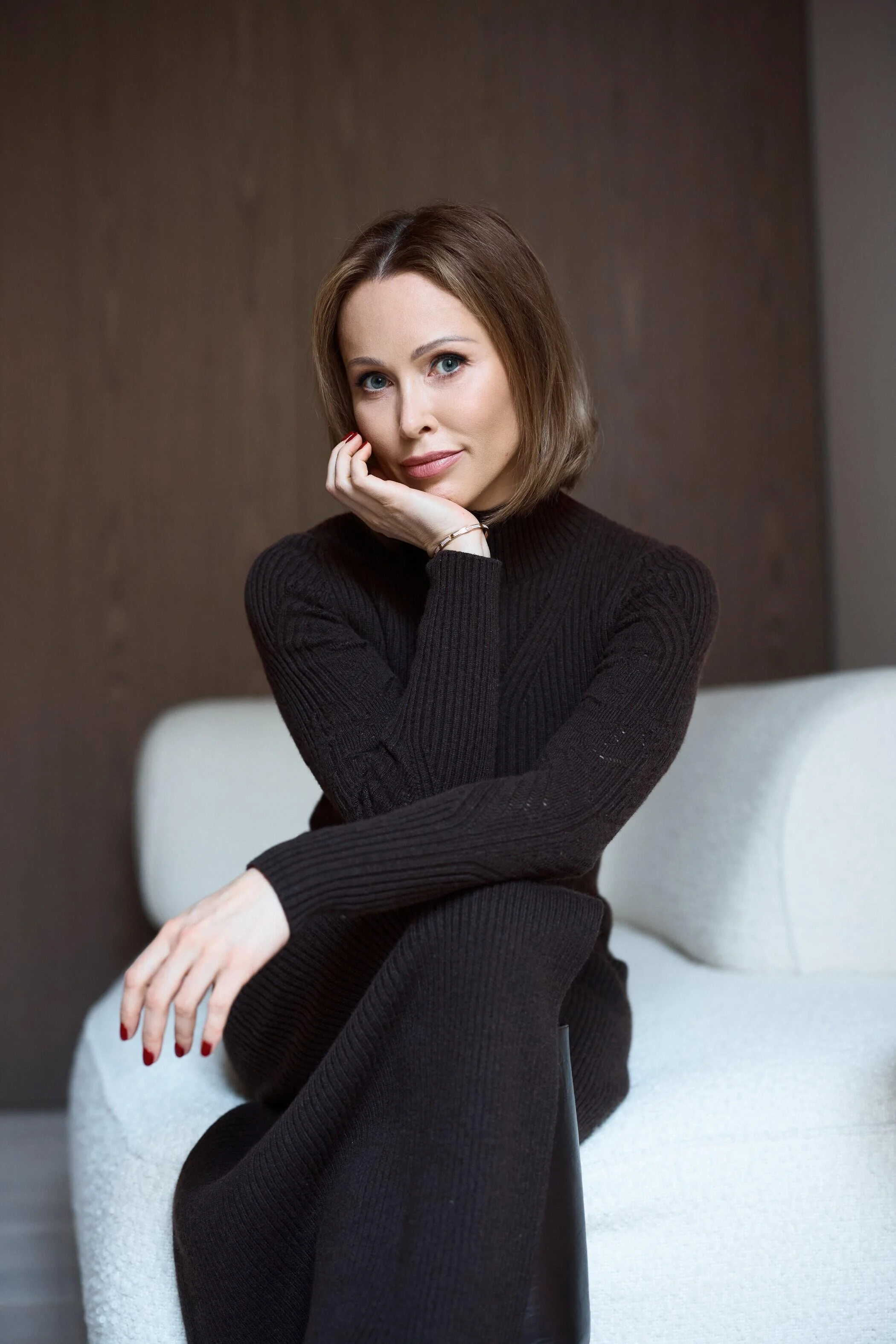 Woman_in_black_sweater_seated_on_a_light_sofa.jpg