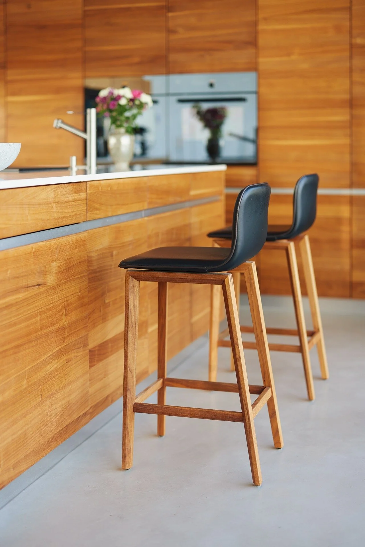 Modern_kitchen_with_wooden_cabinets_and_black_stools.jpeg