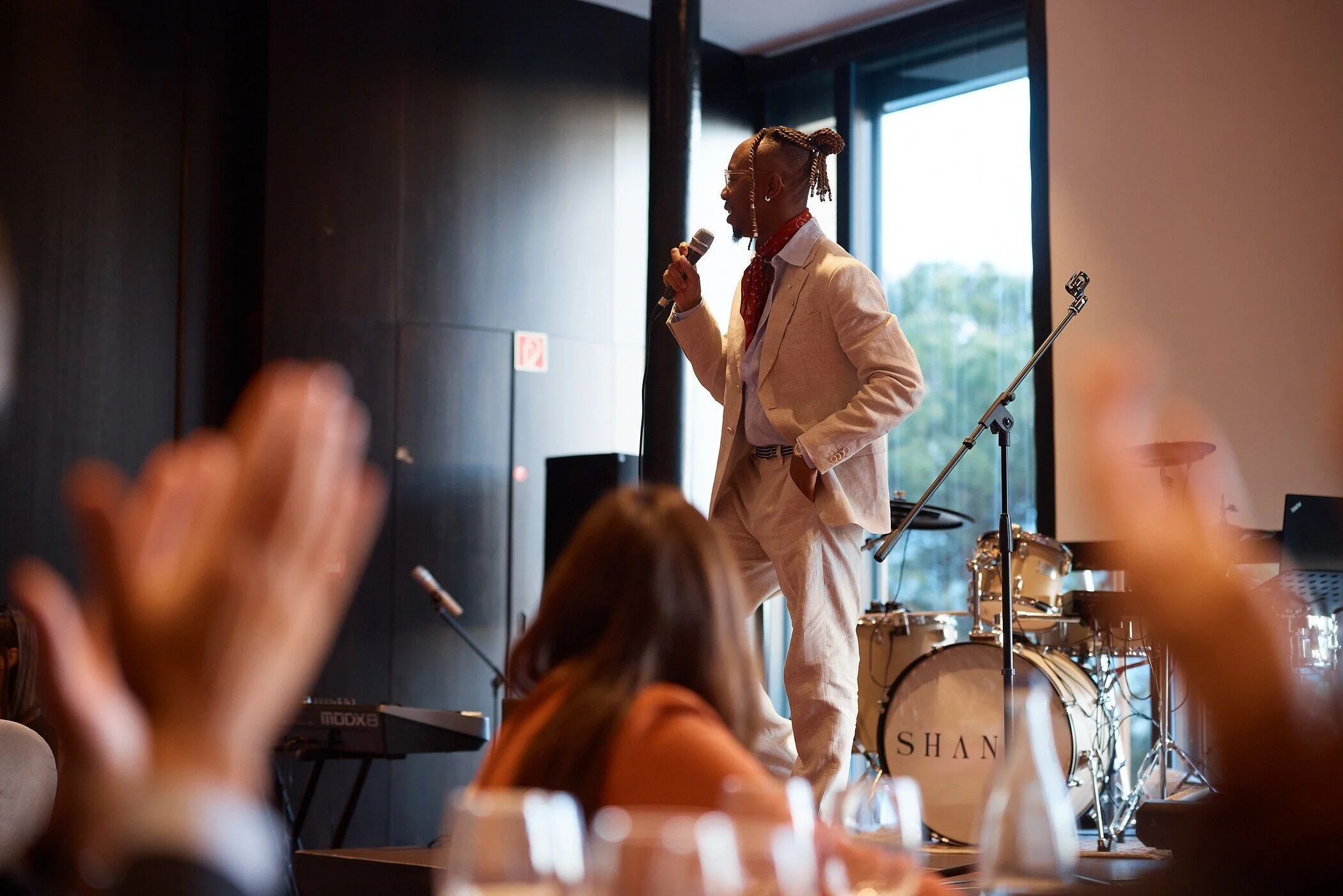 Man_in_light_suit_performing_on_stage_with_microphone.jpg