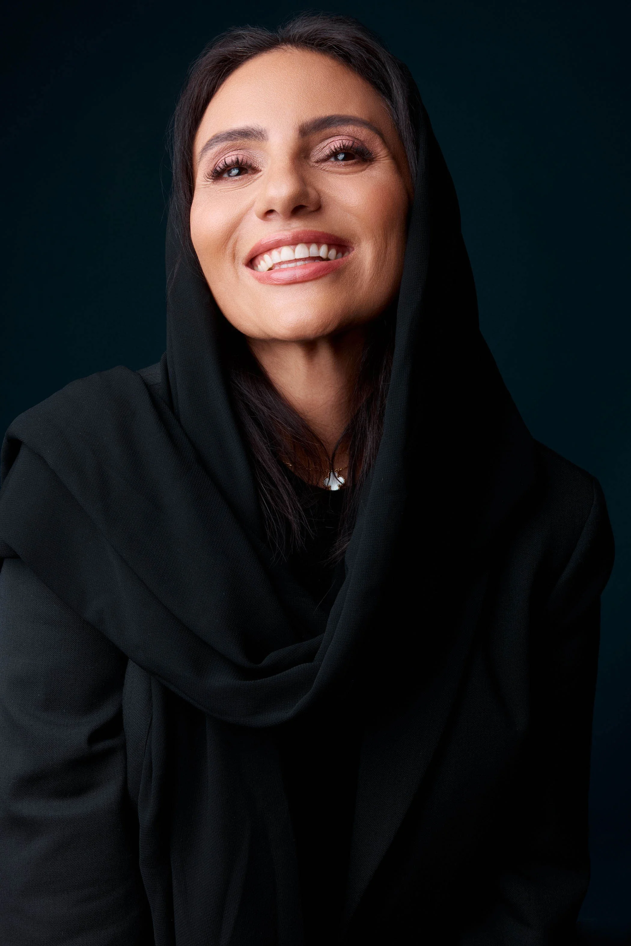 Femme_souriante_en_attire_noire_avec_un_fond_foncé.jpg
