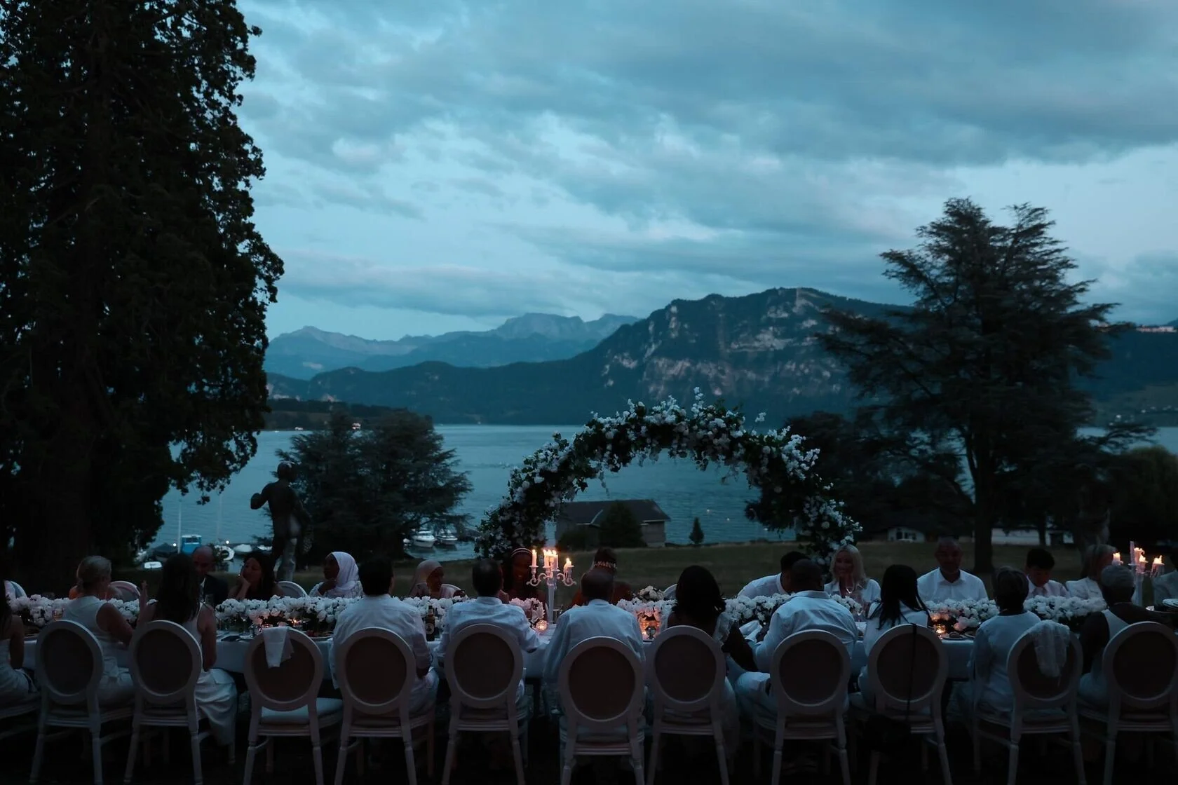 Elegant_outdoor_dinner_party_with_floral_arch_and_lake_view.jpeg