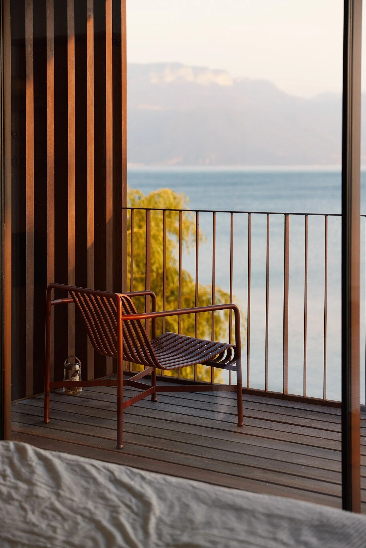 Modern_chair_on_balcony_overlooking_lake_and_mountains.jpeg