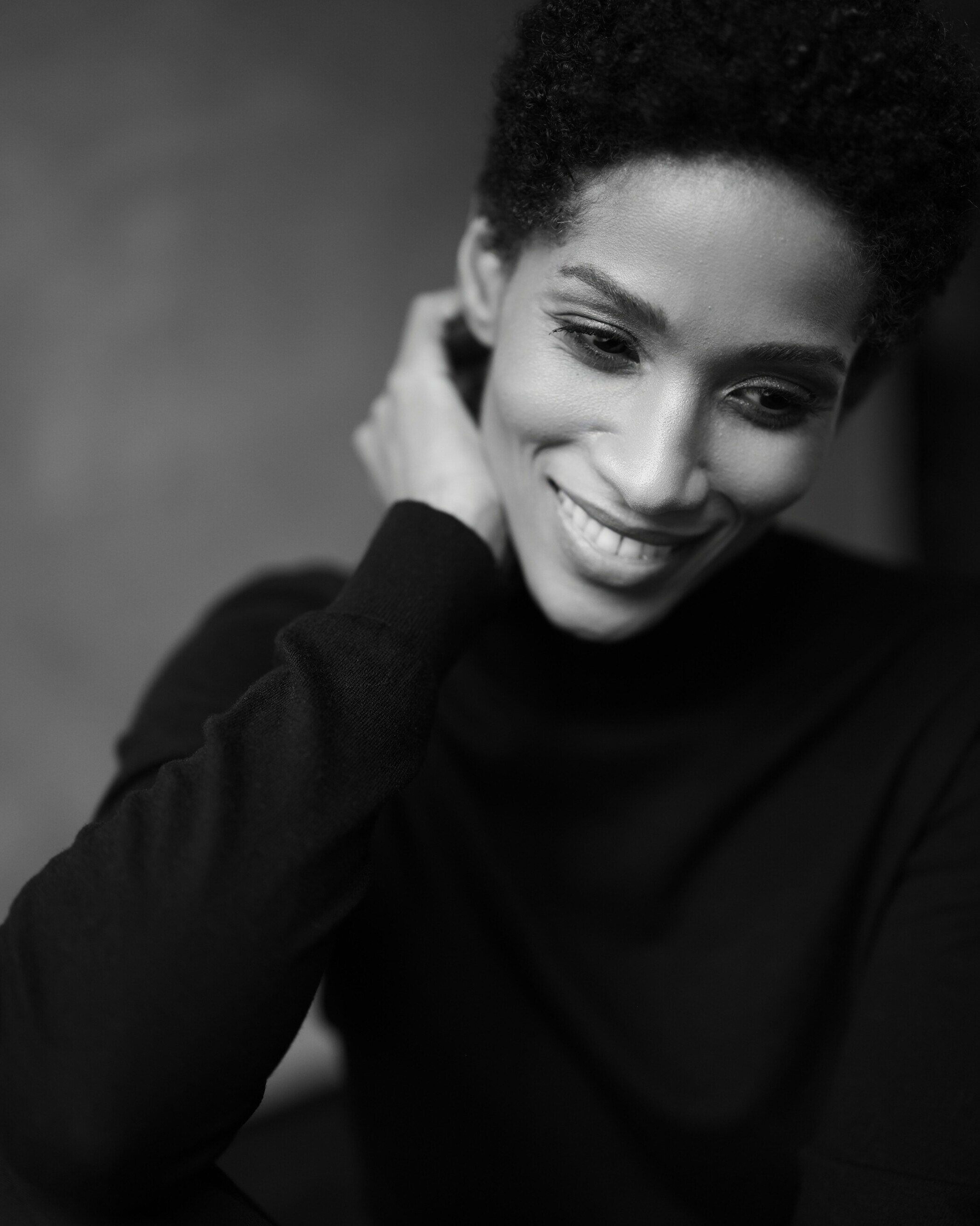 Smiling_woman_in_black_turtleneck_soft_lighting_close-up.jpg