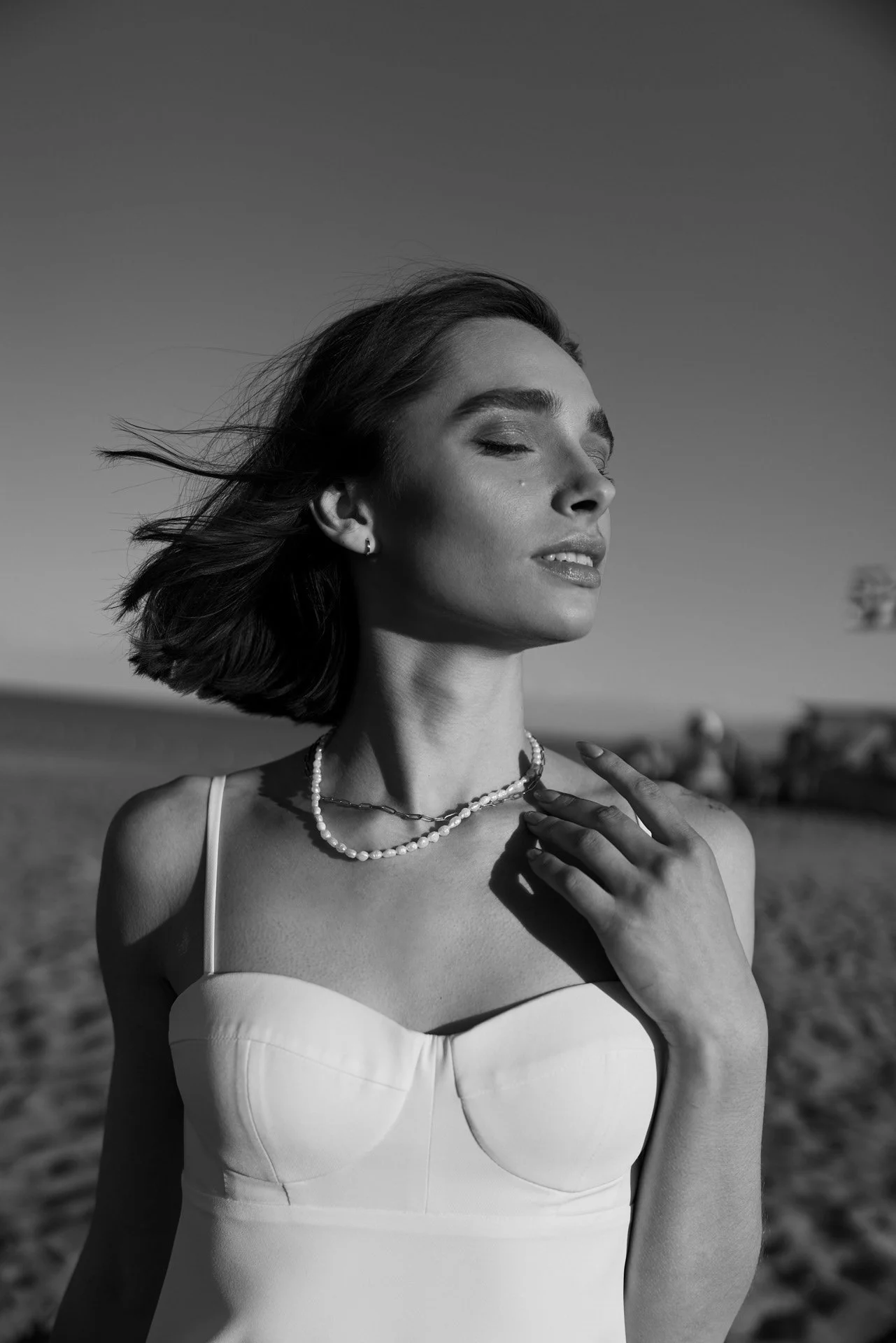 Femme_en_robe_blanche_avec_des_perles_sur_la_plage.jpeg
