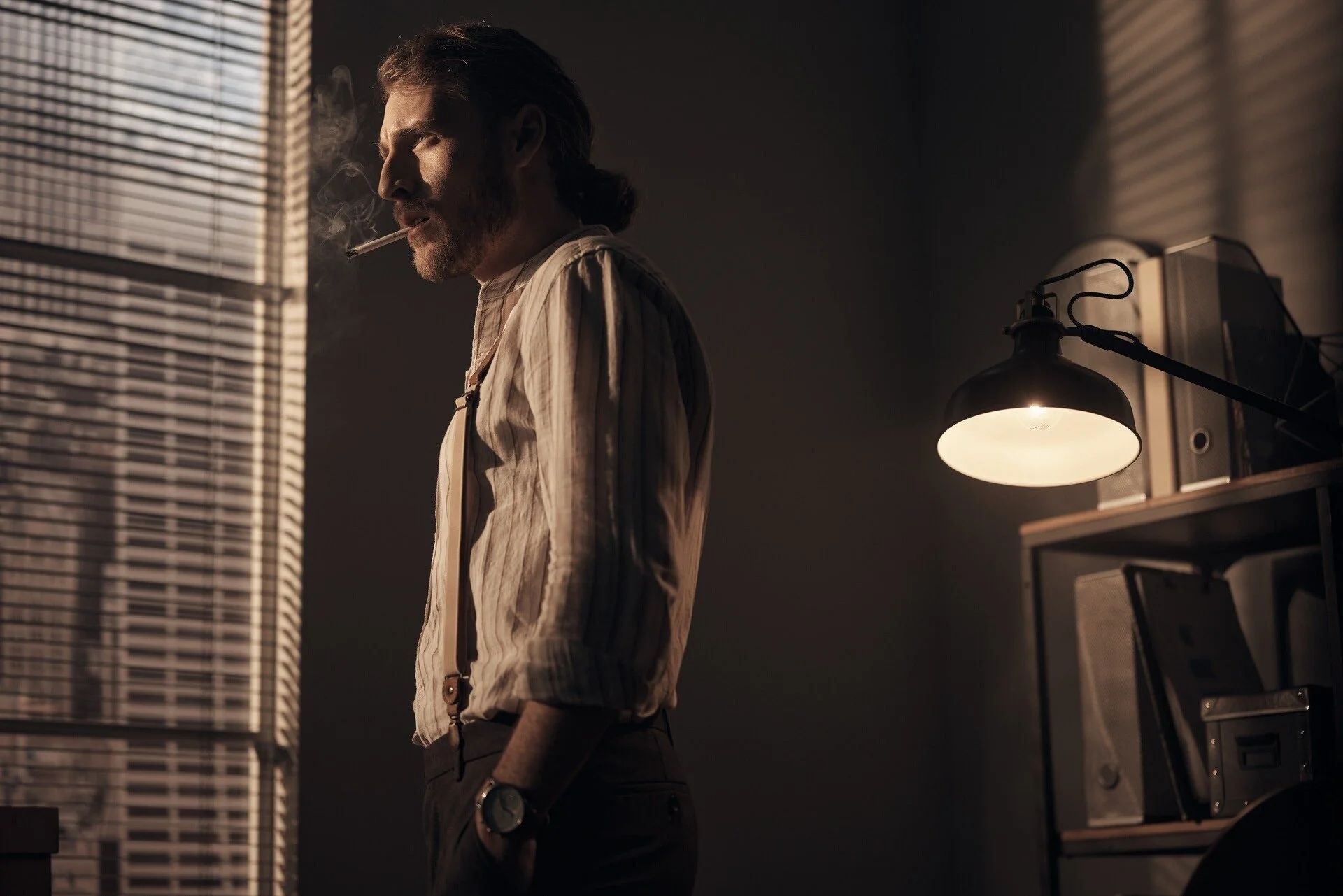 Man_in_striped_shirt_with_suspenders_smoking_in_dim_room.jpeg