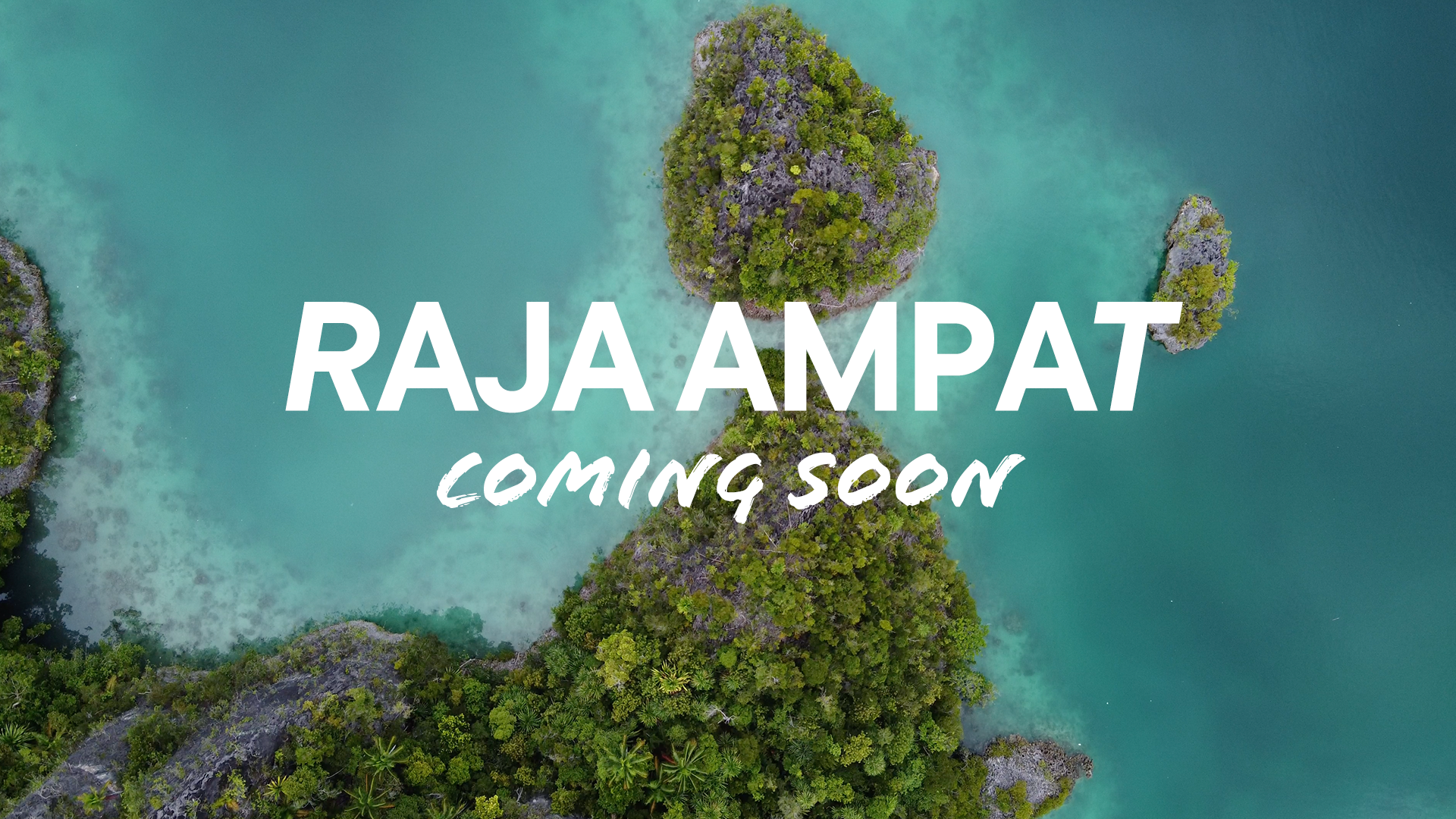 Aerial view of a tropical island with lush green trees surrounded by turquoise water, with the text 'RAJA AMPAT COMING SOON' overlaid.