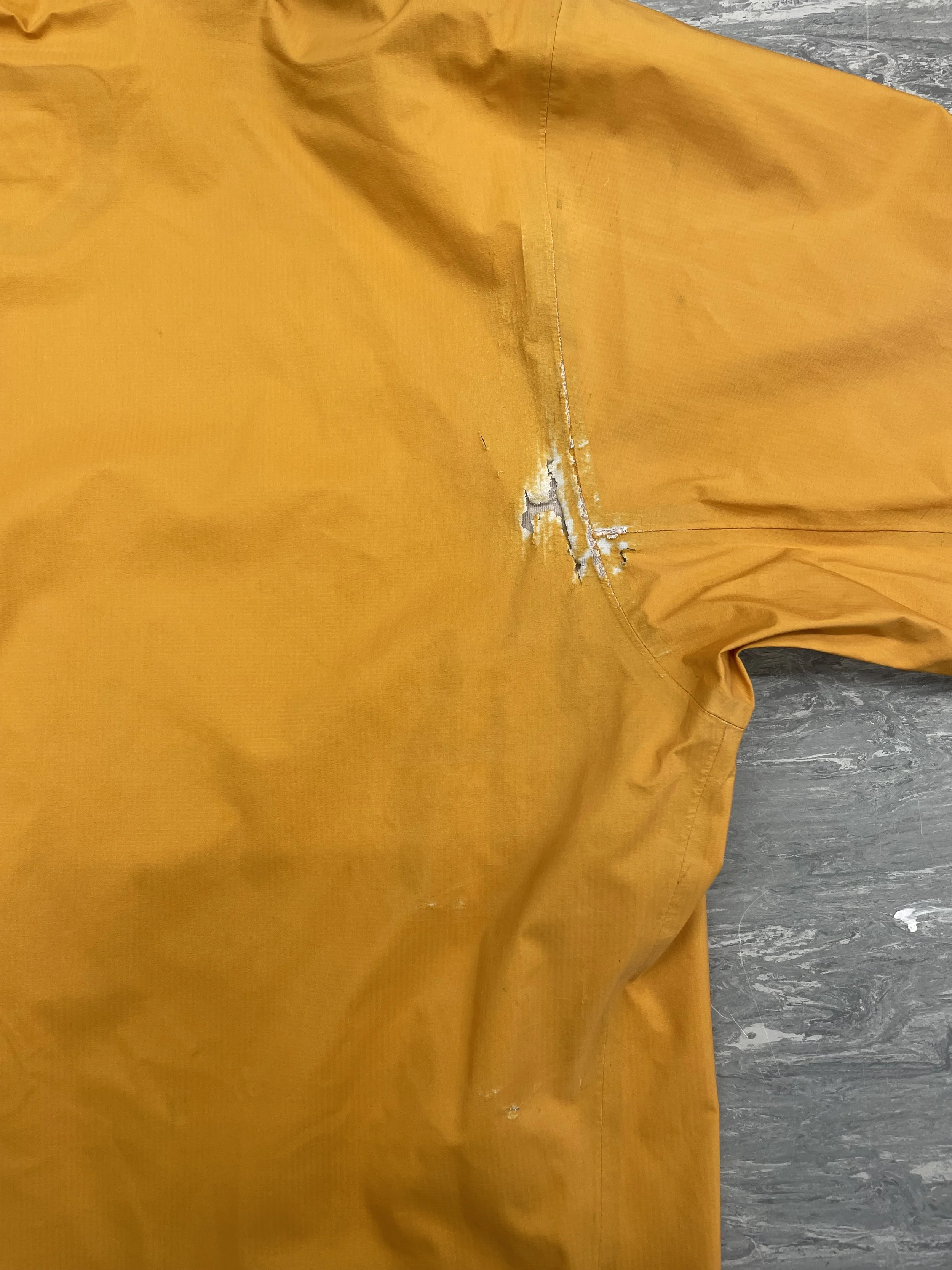 Worn and abraded area to underarm of waterproof coat