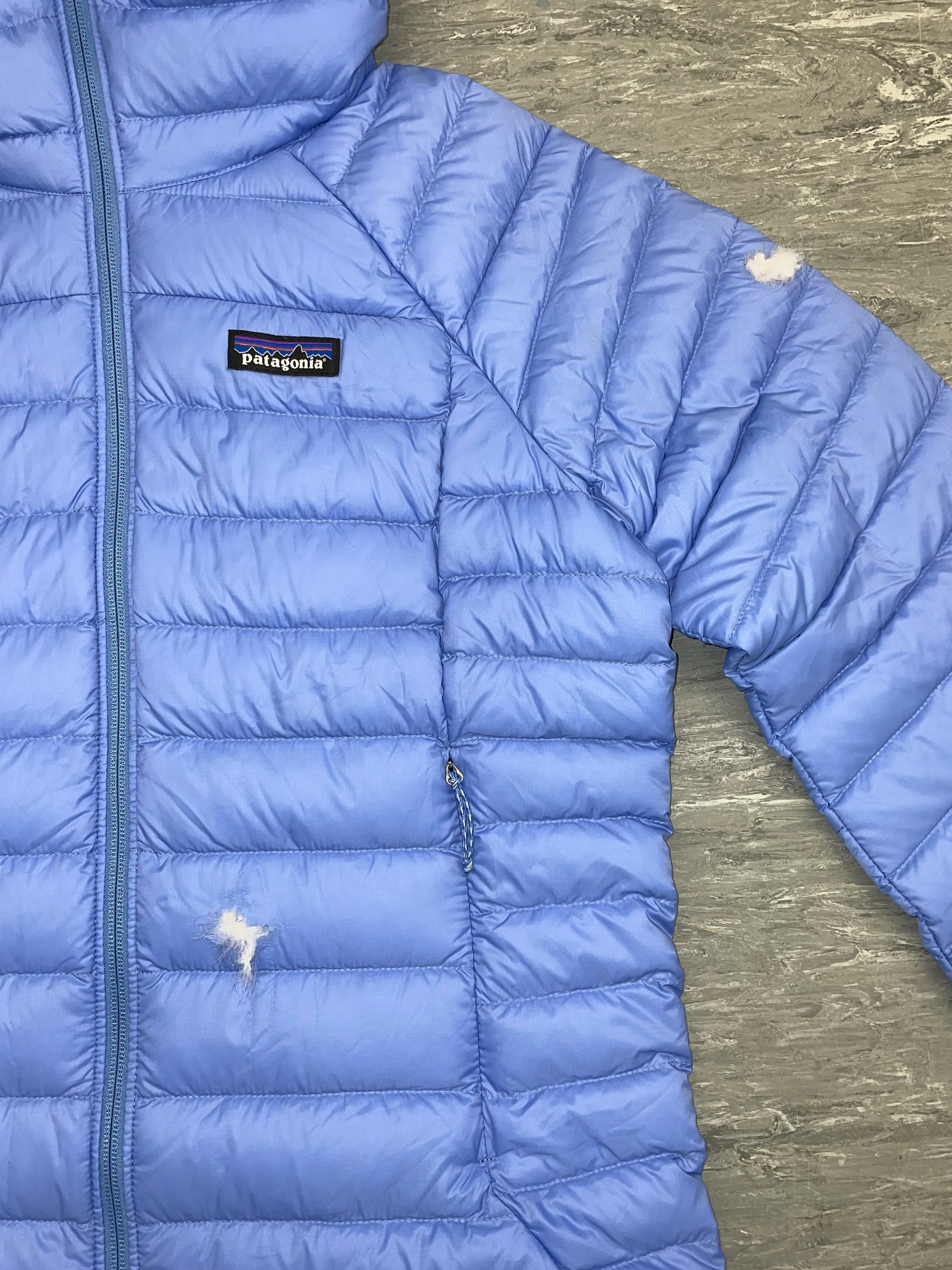 Multiple holes to front and sleeve of Patagonia coat, with down escaping