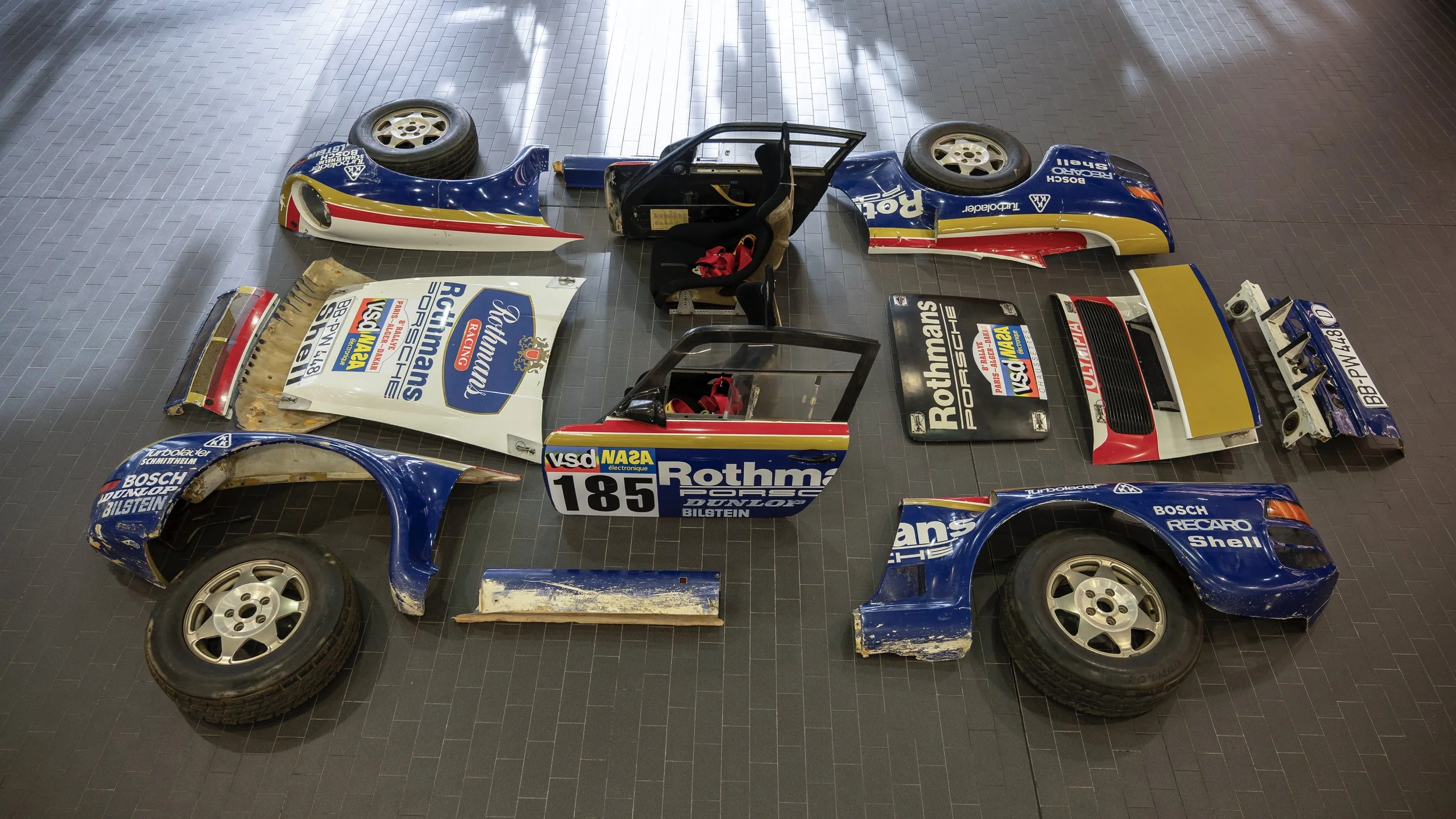 Disassembled body panels and components of the Sikkens Motorsport Dakar heritage project car during restoration process