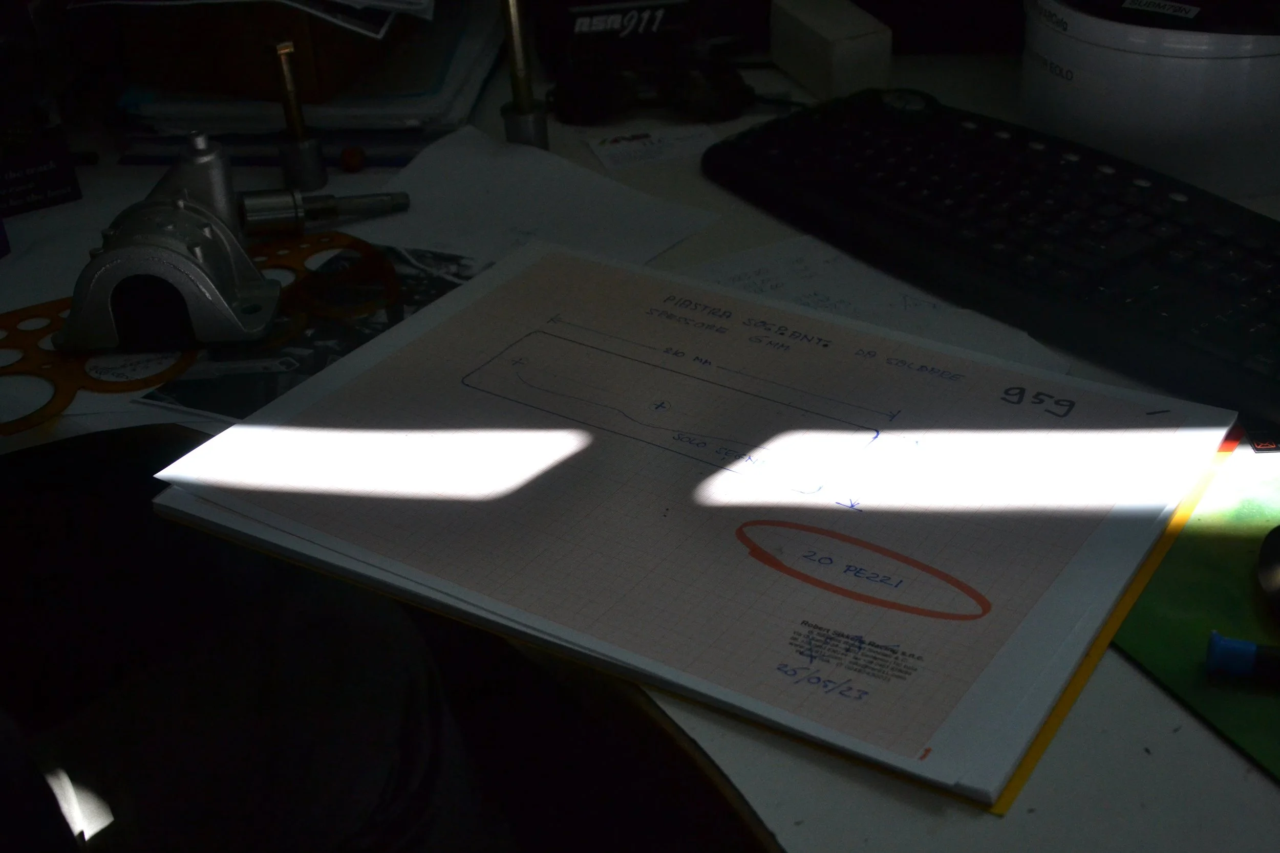 Workspace with handwritten notes and mechanical components used in Sikkens Motorsport Dakar heritage project planning