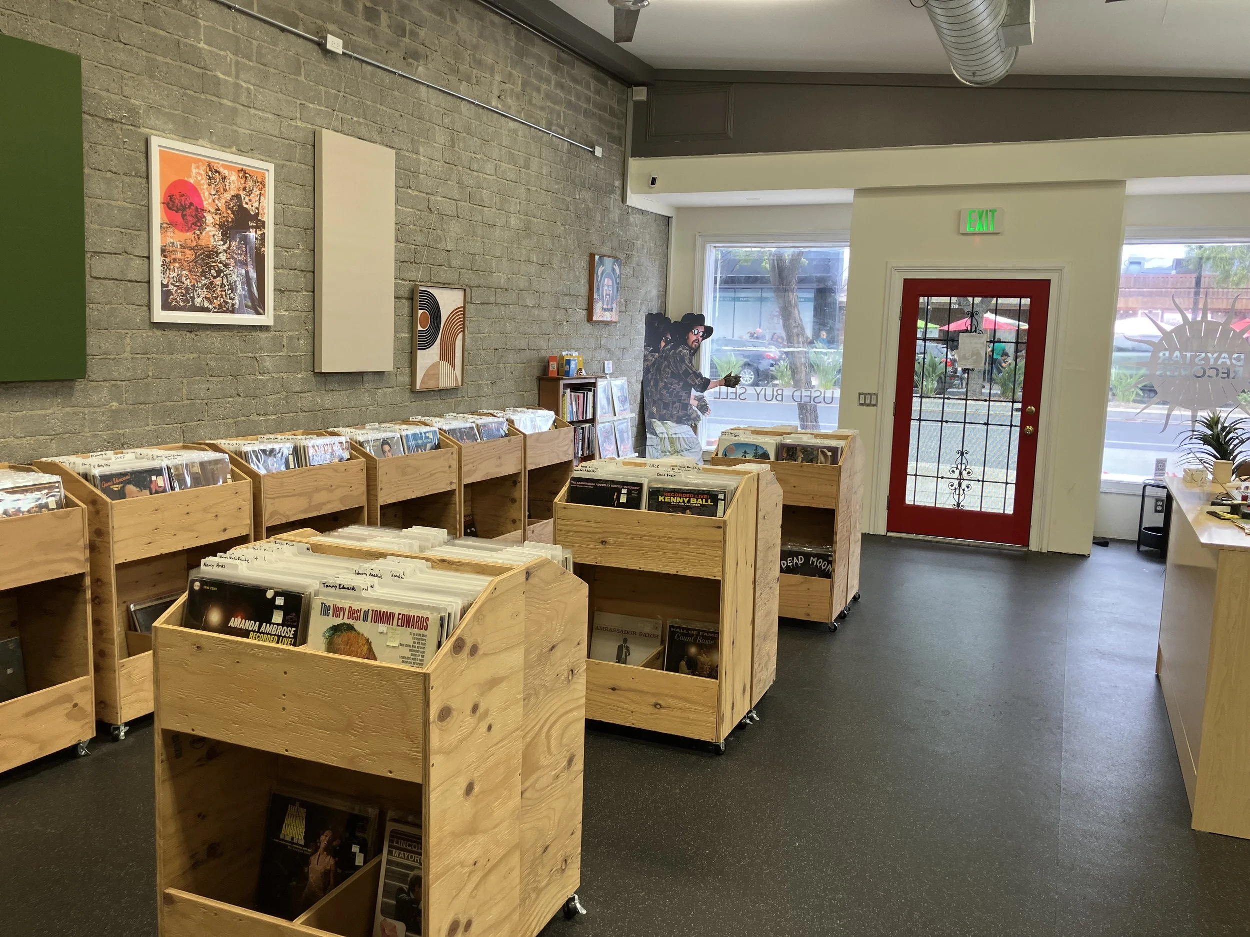 Inside Daystar Records in Burbank, California. Loaded record bins rest comfortably near the exposed gray brick wall with excellent wall art and sound panels for music performance.