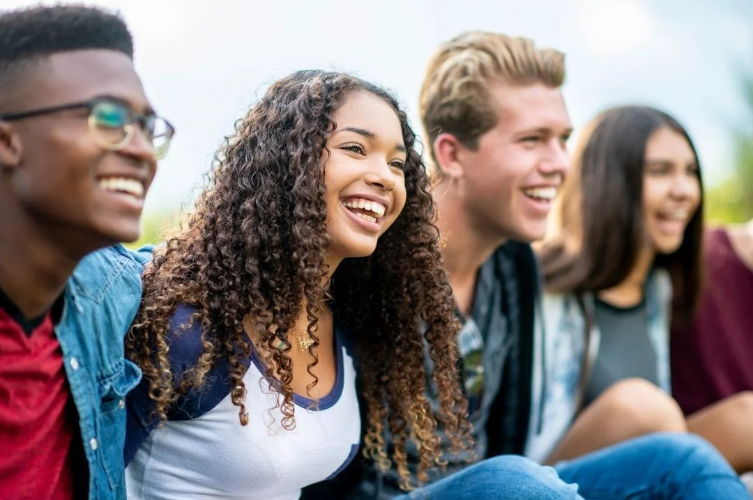 Group of diverse young adults smiling and enjoying outdoors.