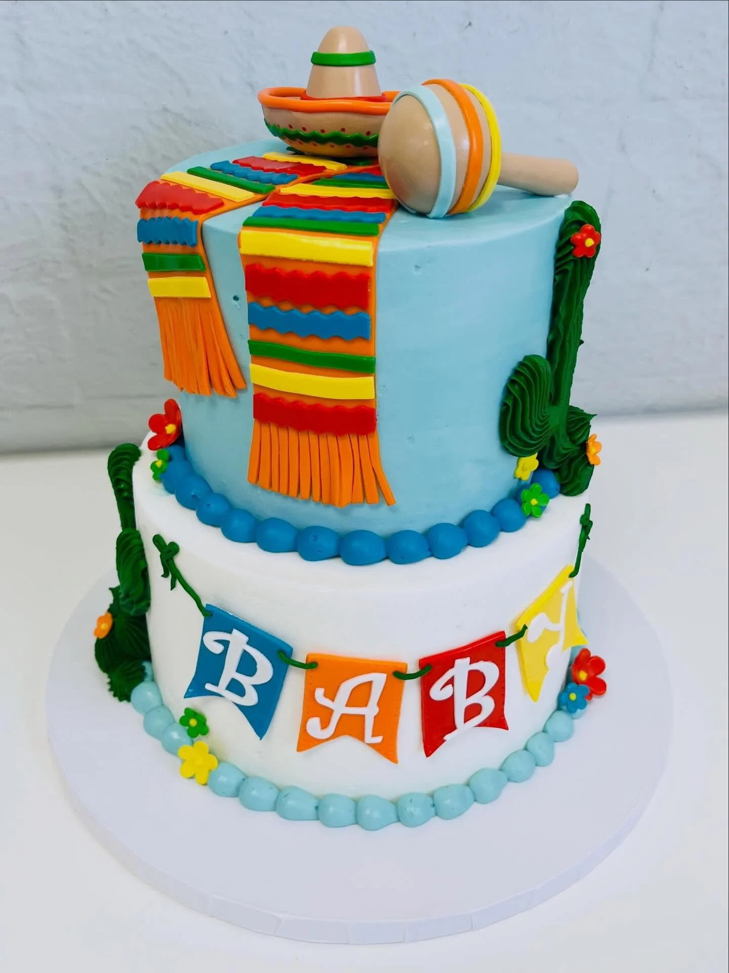 Welcoming a sweet little baby with this colorful fiesta-inspired baby shower cake! 🌵🎉 From the tiny sombrero and rattle on top to the vibrant scarf details and cactus accents, every piece was made to celebrate a joyful new arrival! #BabyShowerCake 