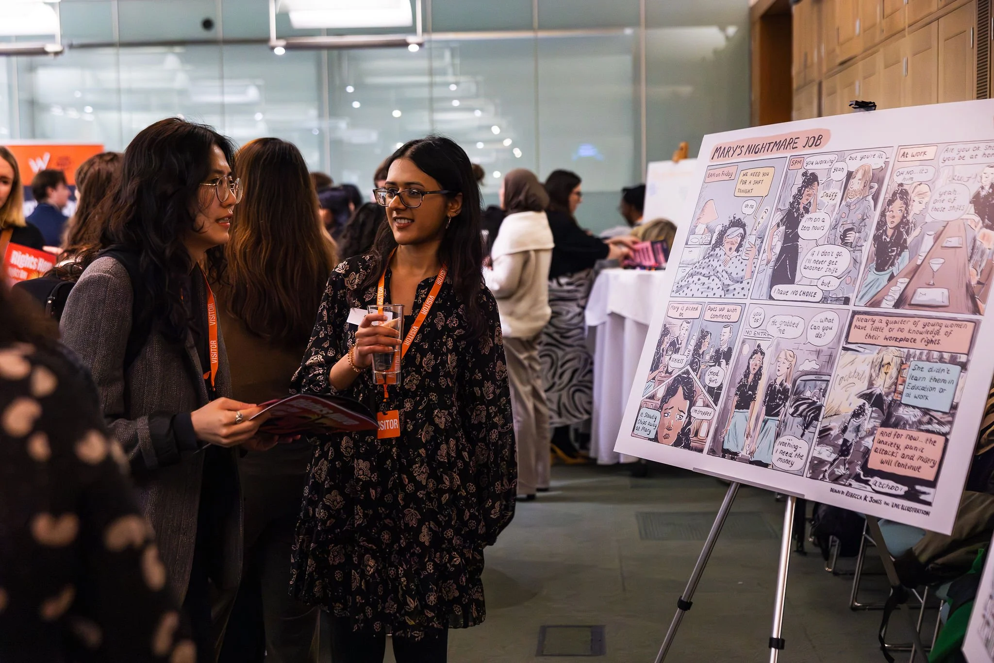 Two women looking at a foam board print of a comic strip