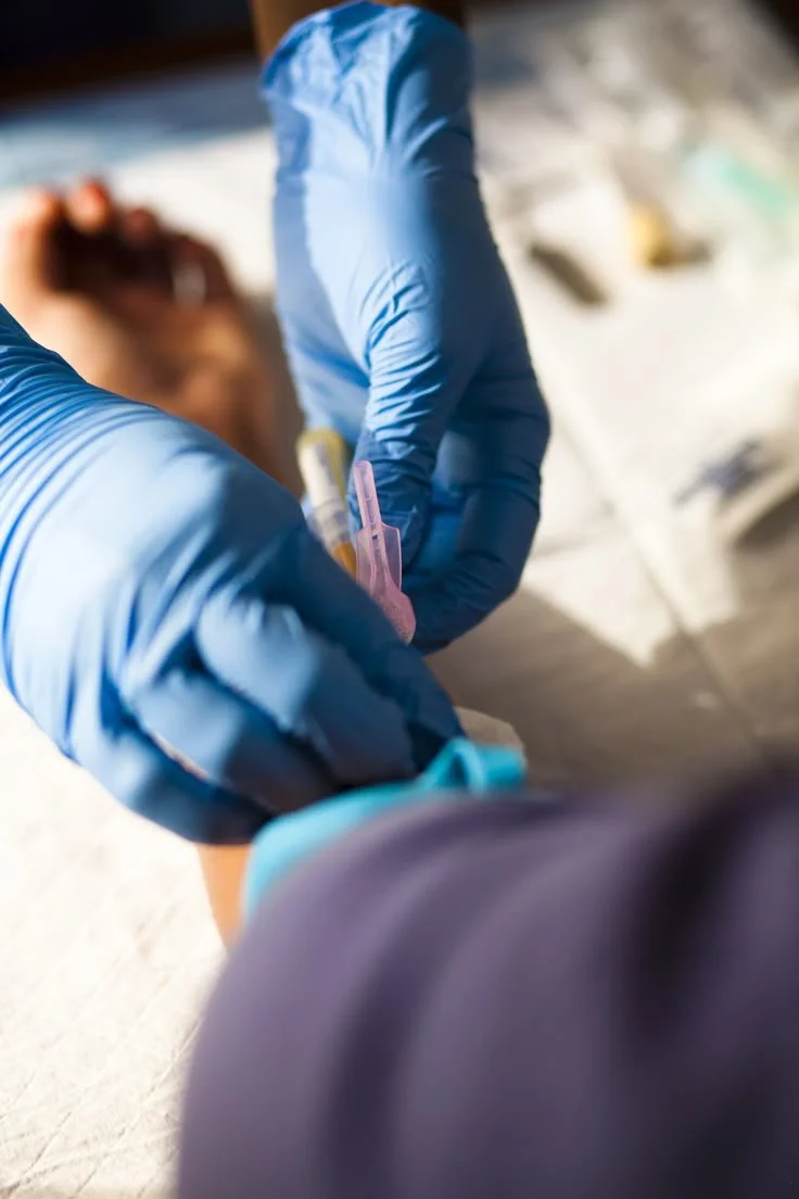 Healthcare worker in blue gloves administering a vaccine or shot to a person.