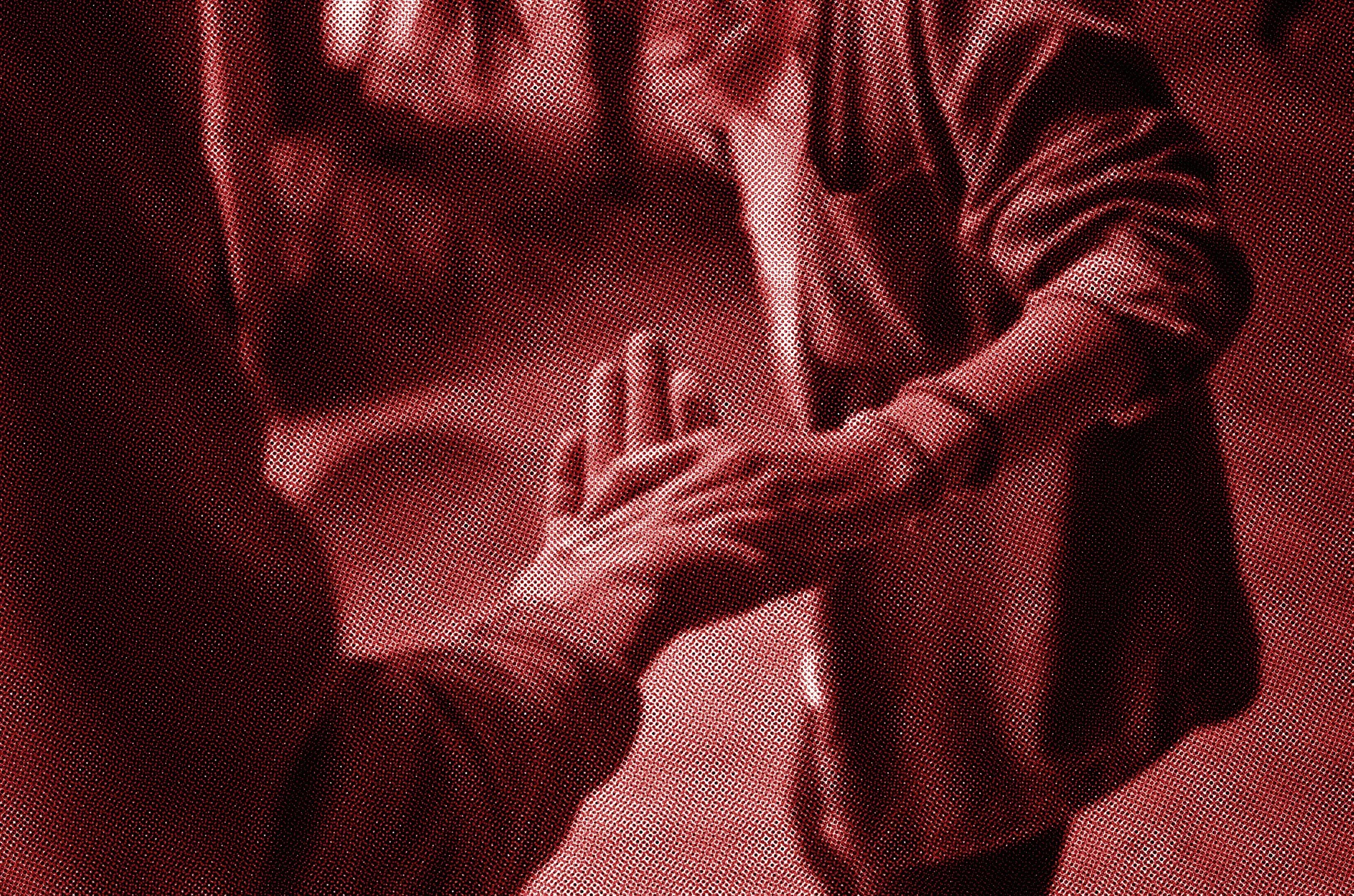 Close-up of two people holding hands, with one person's hand over the other's. Both are wearing long-sleeved clothing; one jacket sleeve is visible.