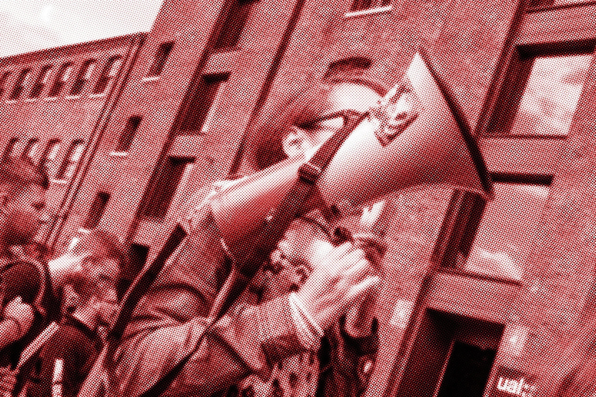 Close-up image of a mechanical or industrial part involving pipes and a valve or handle, with a building or structure in the background.
