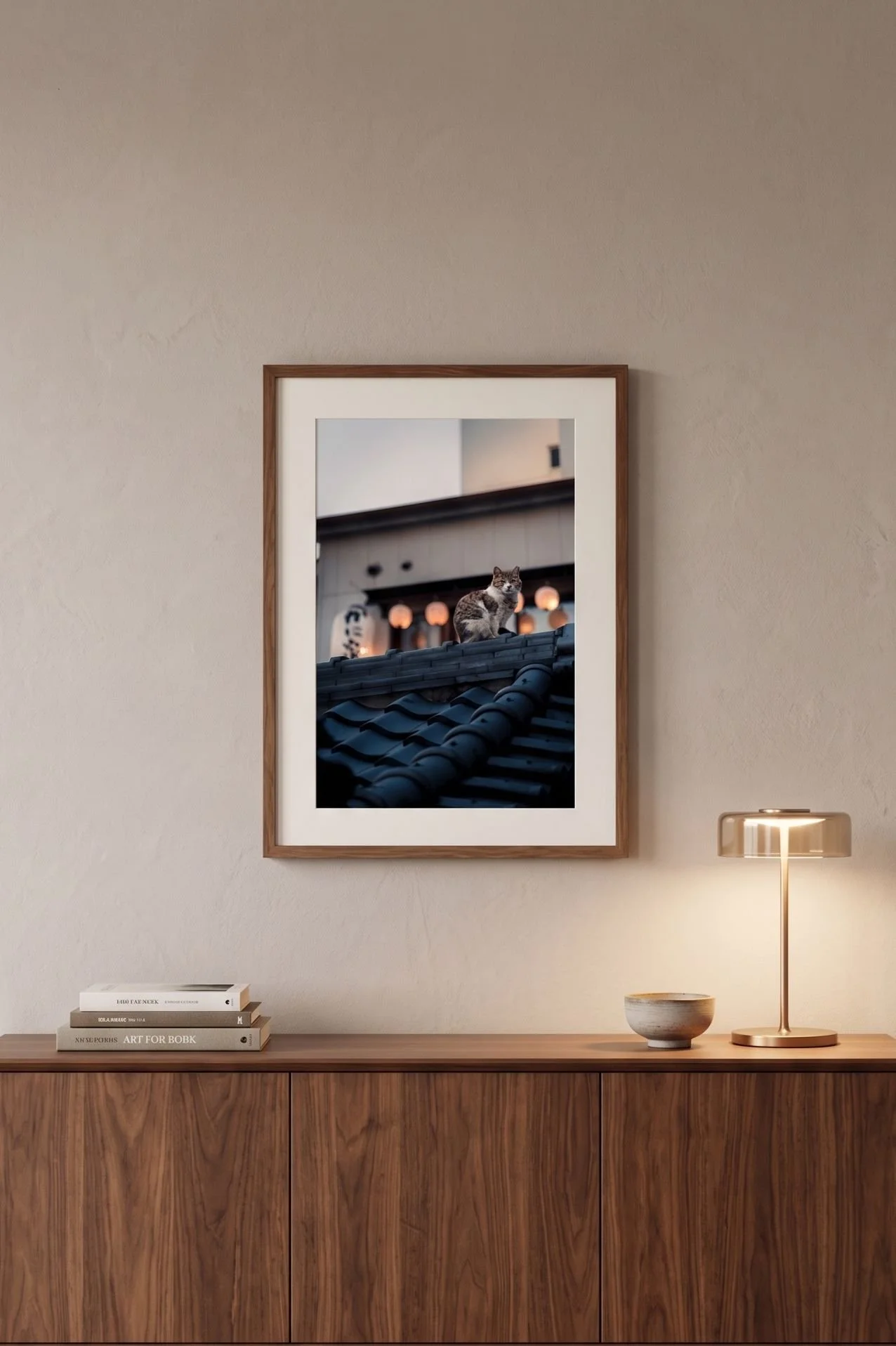 Cat and lanterns print in a black frame on a warm golden-hour wall.