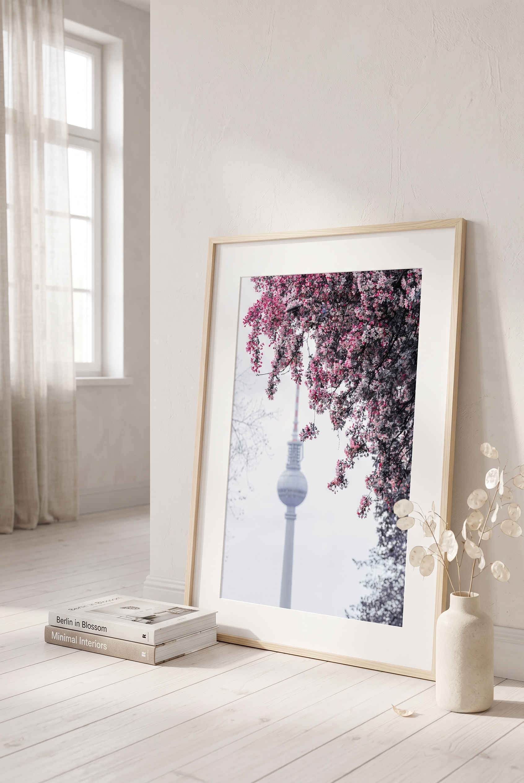Cherry blossoms framing the soft-focus Berlin Fernsehturm TV tower against a pale spring sky.