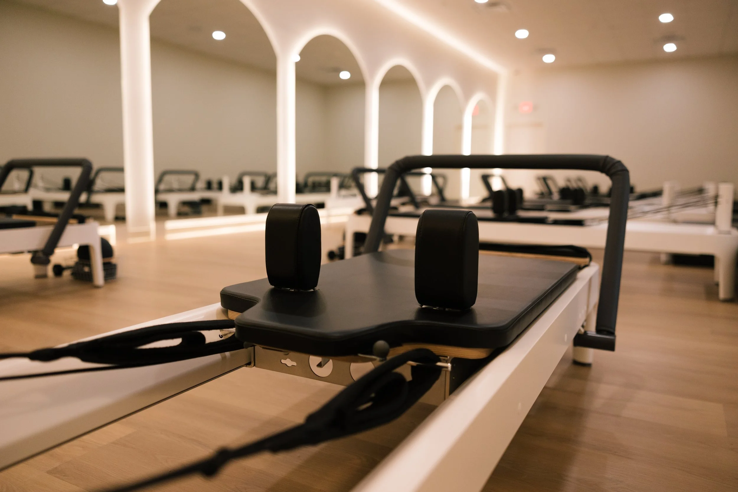 Pilates reformer machine in a spacious, well-lit studio with arched ceiling design.