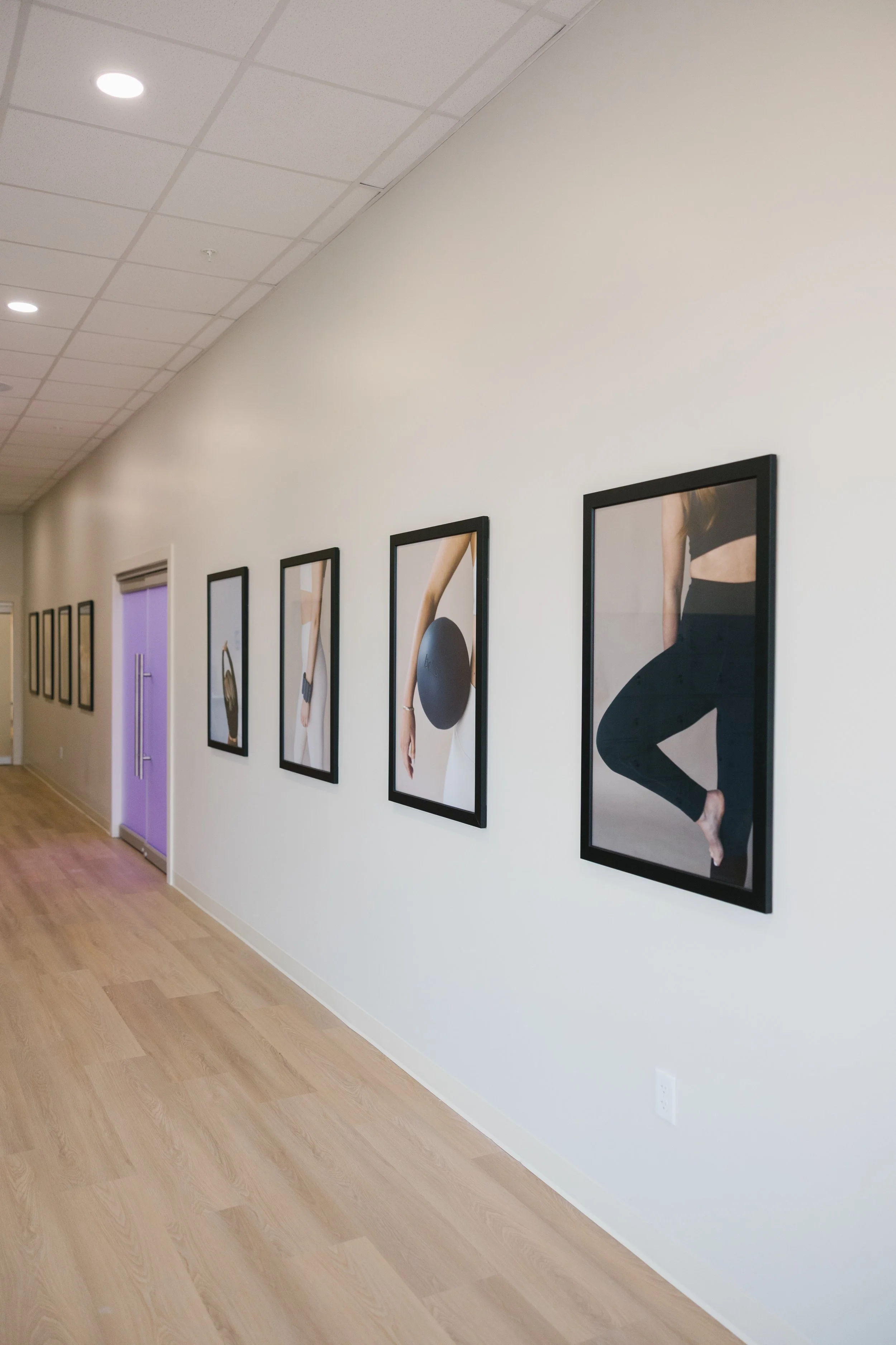 Gallery wall with framed photographs of people practicing yoga or meditation in a fitness studio.