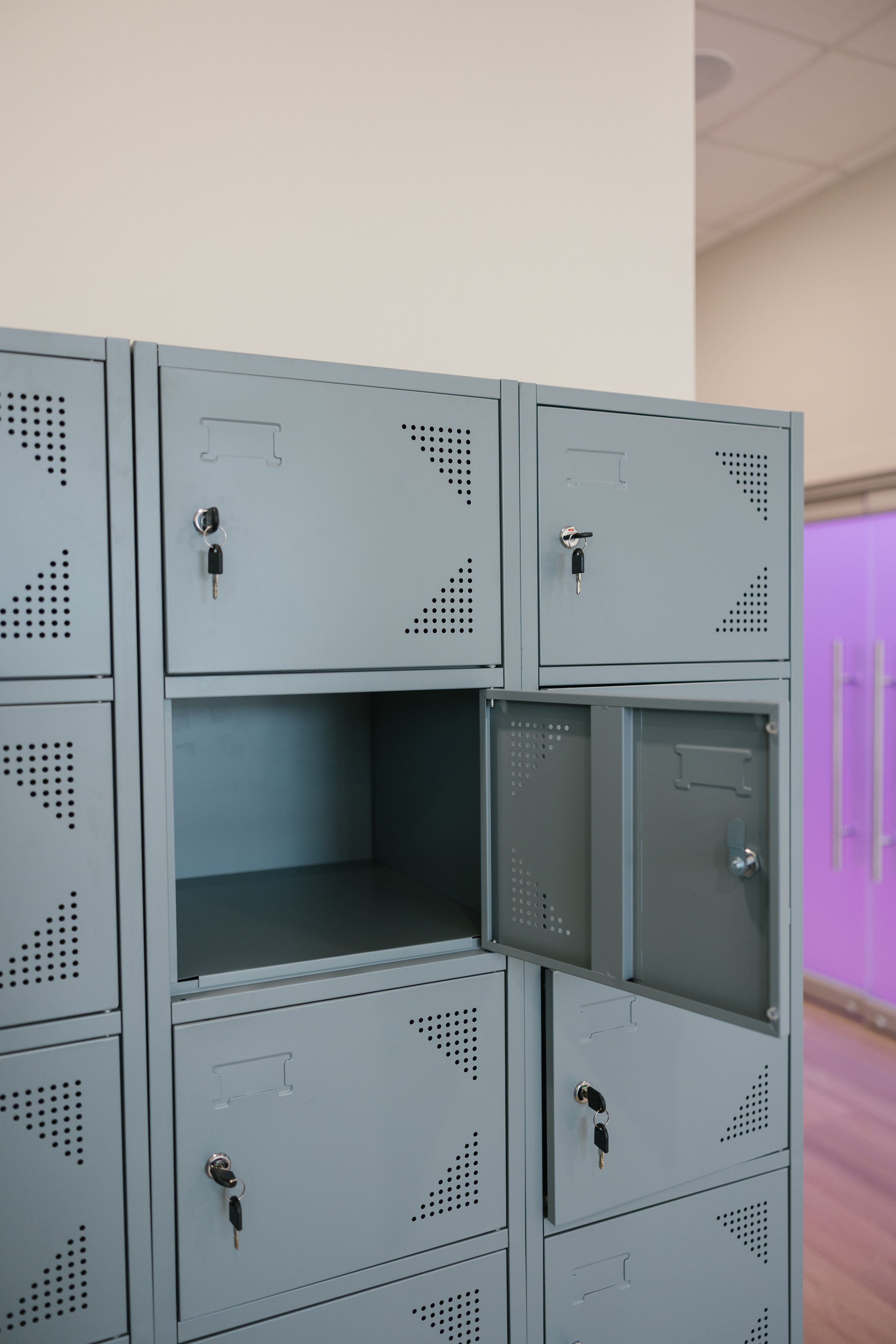 Empty light gray metal lockers with small lock keys in a school or office setting.