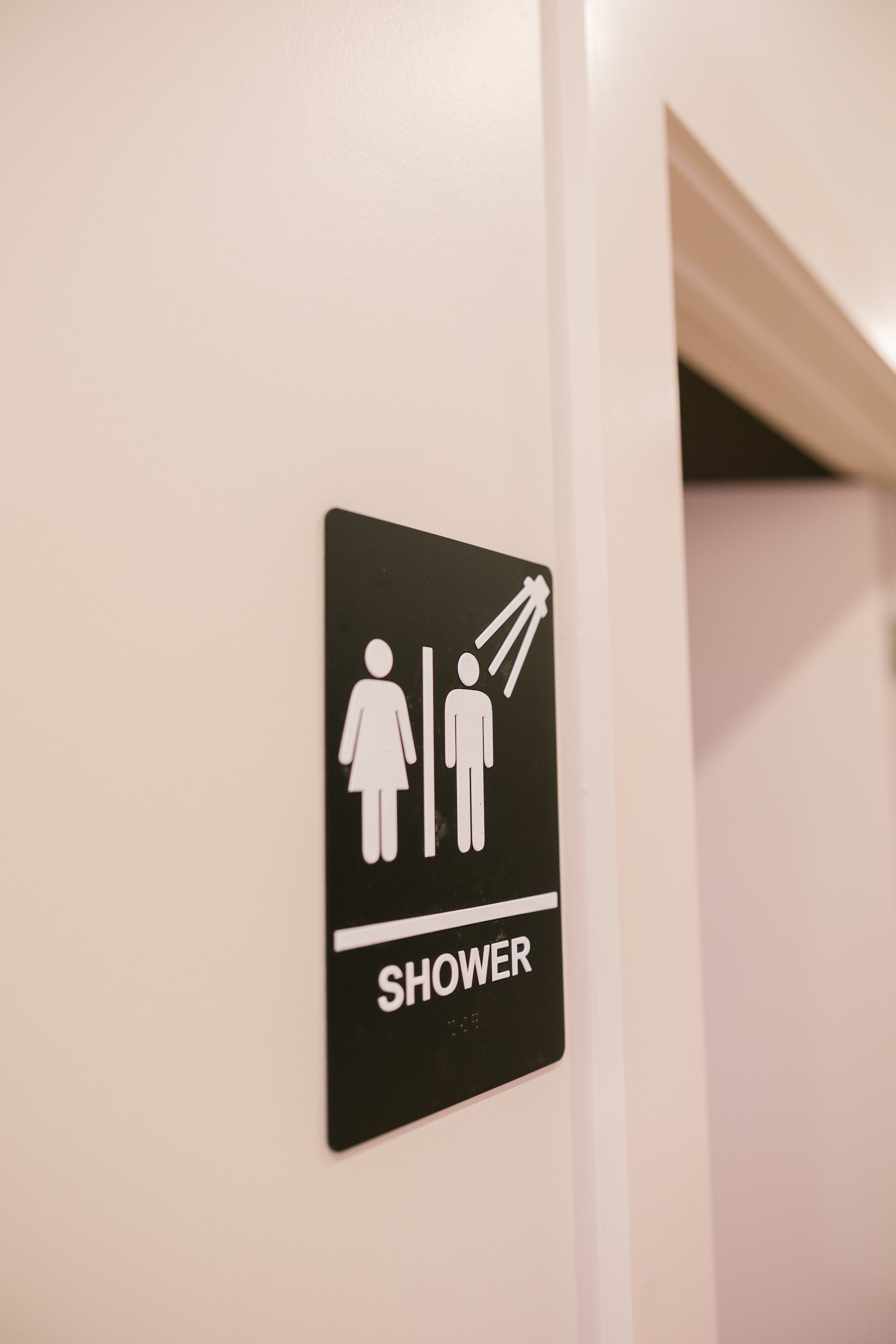 Sign indicating a women's and men's shower area with a directional arrow.