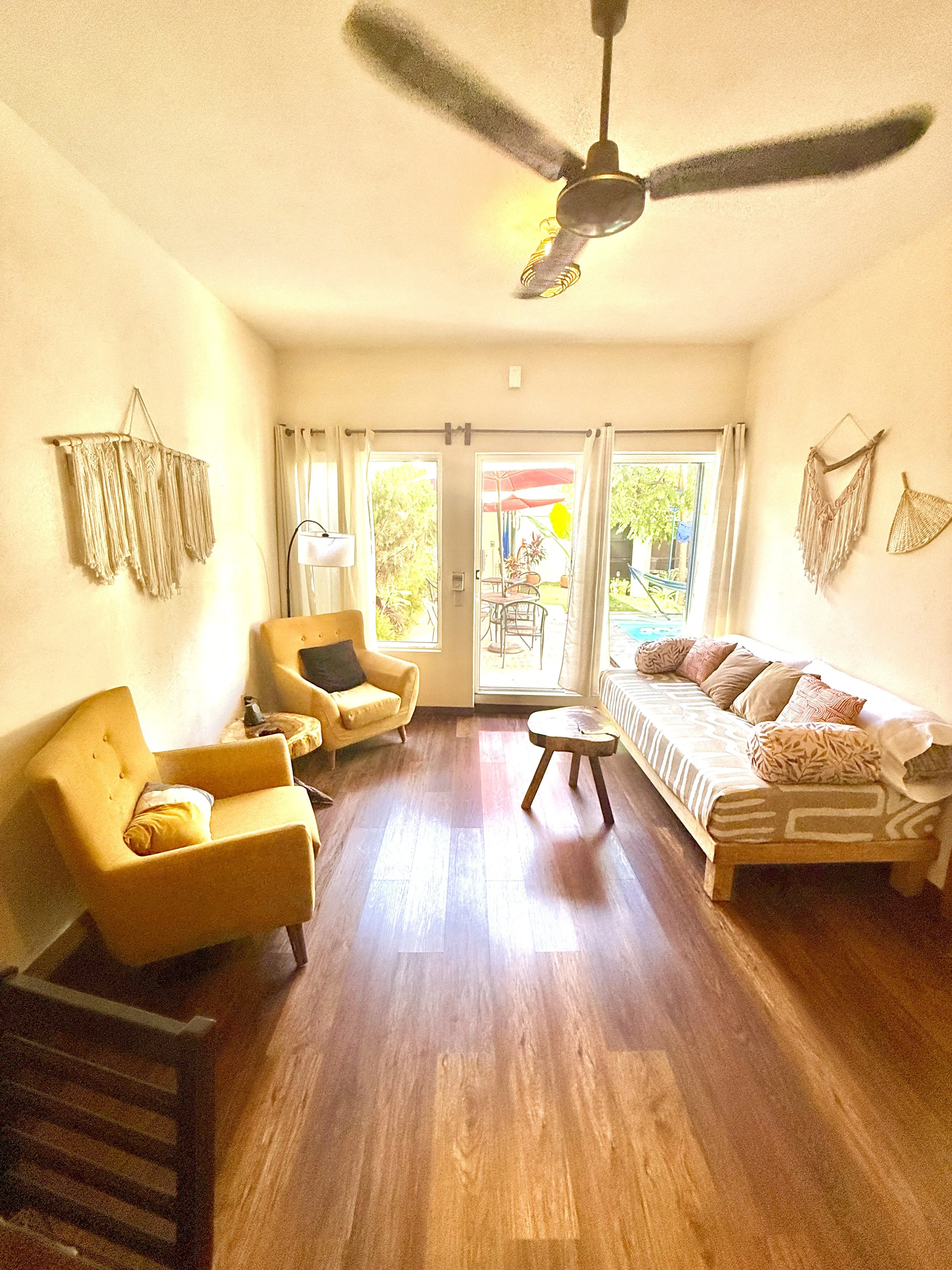 Interior of a room with yellow walls, a large wooden dining table with chairs, a built-in corner bench, and a hammock.