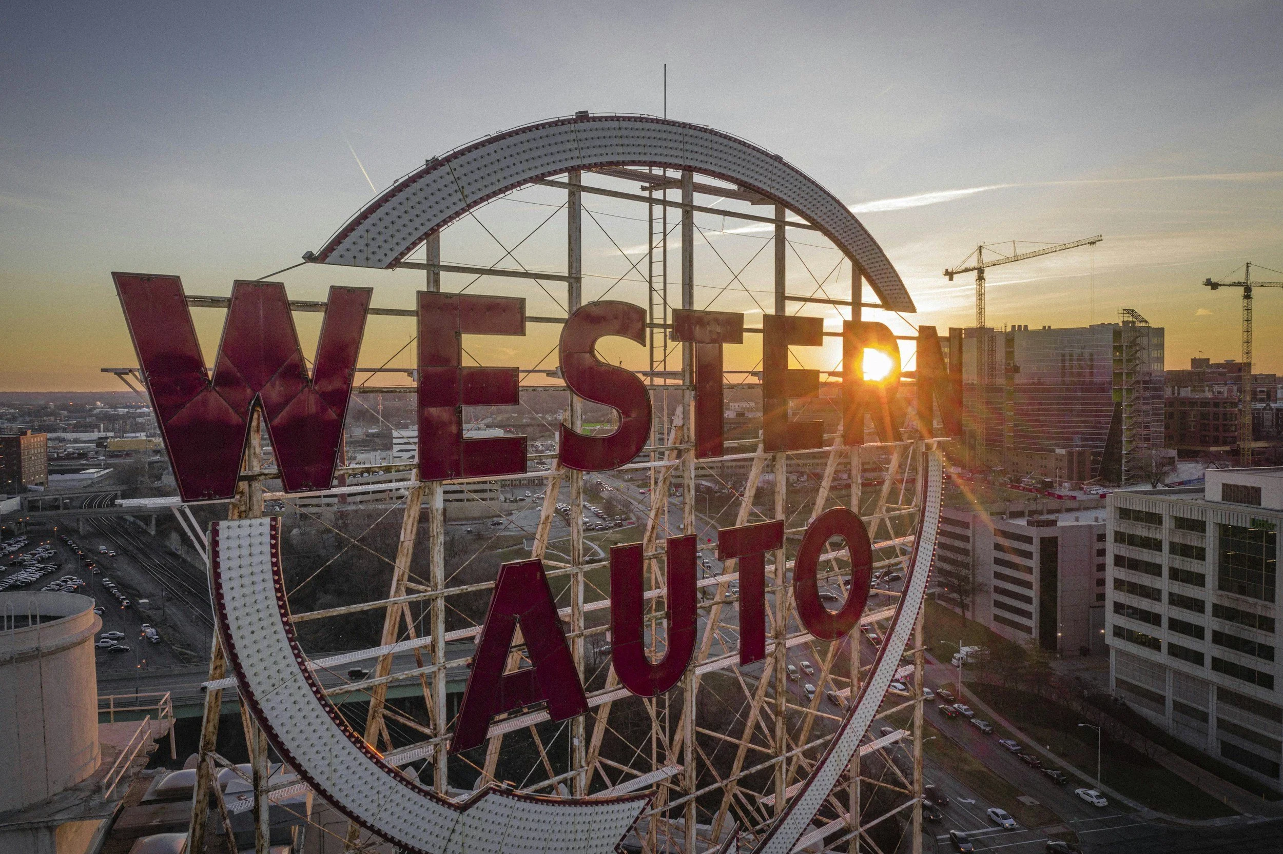 The illuminated Sunset Inn sign on the Ferris wheel at sunset in Nashville, Tennessee, with construction cranes and buildings in the background.