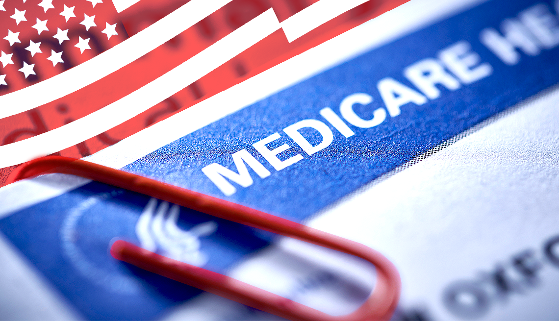 Close-up of a medicare card and a red paperclip on a document with part of an American flag in the background.