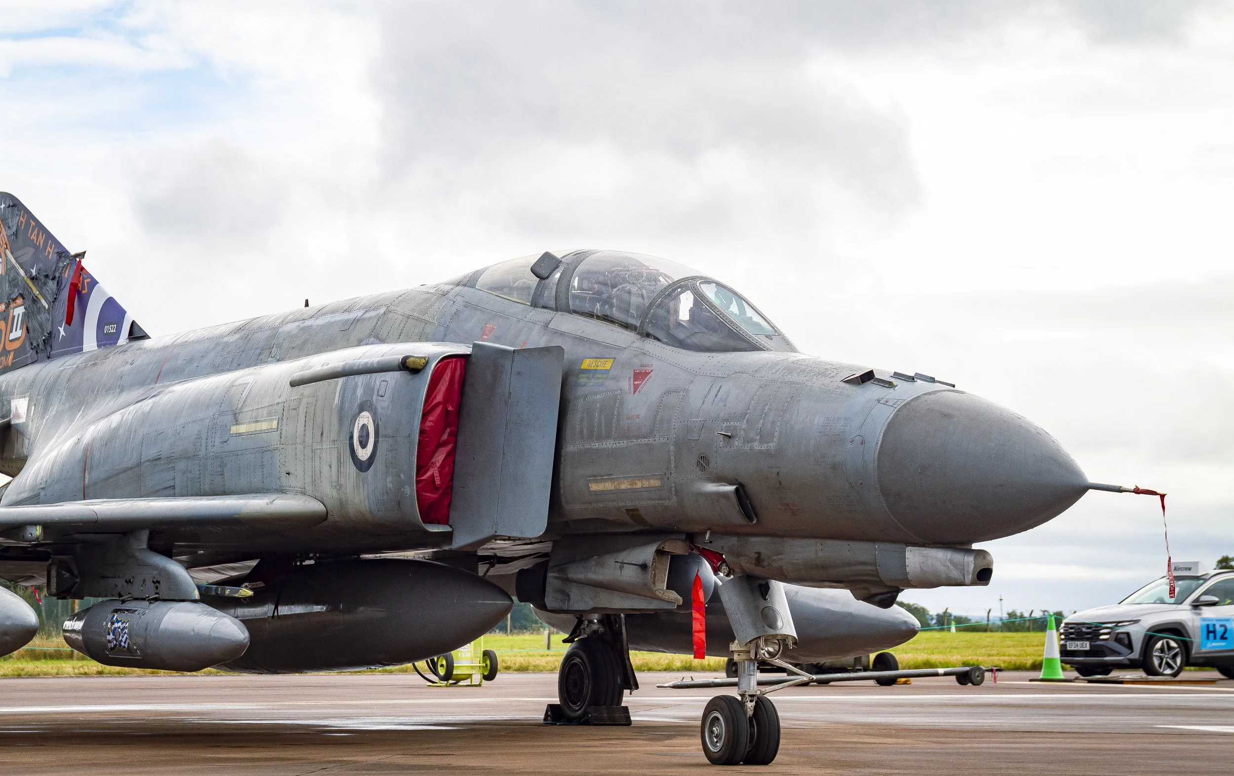 A fighter jet parked on an airstrip with a cloudy sky in the background.