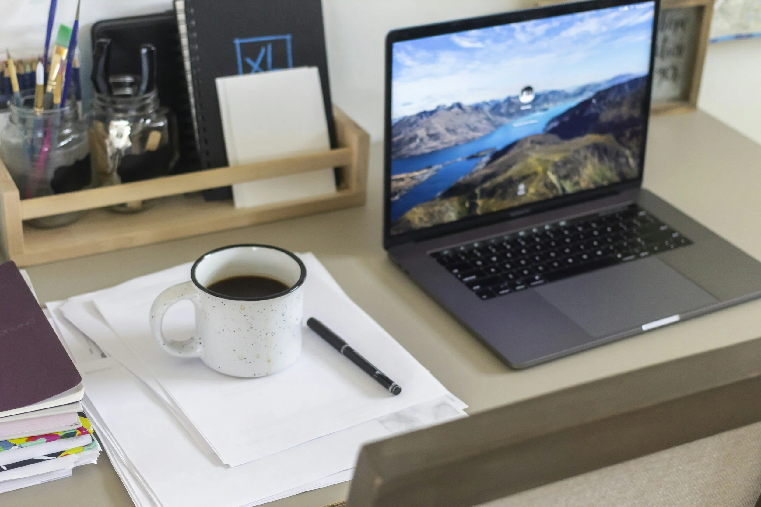 A minimalist home office desk with a laptop and a warm drink, representing quiet luxury and professional mental health.