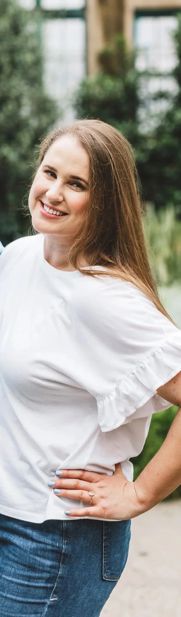 A woman with long brown hair is smiling and wearing a white shirt. She is a therapist for anxious overachievers in Pennsylvania and New York.