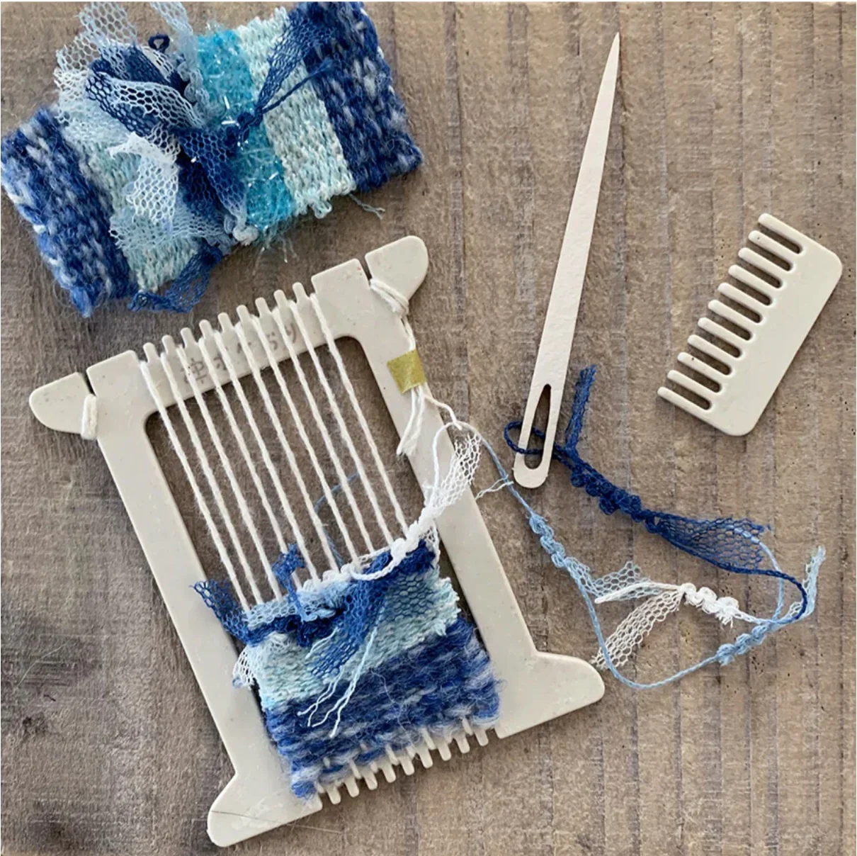 small weaving loom with blue threads