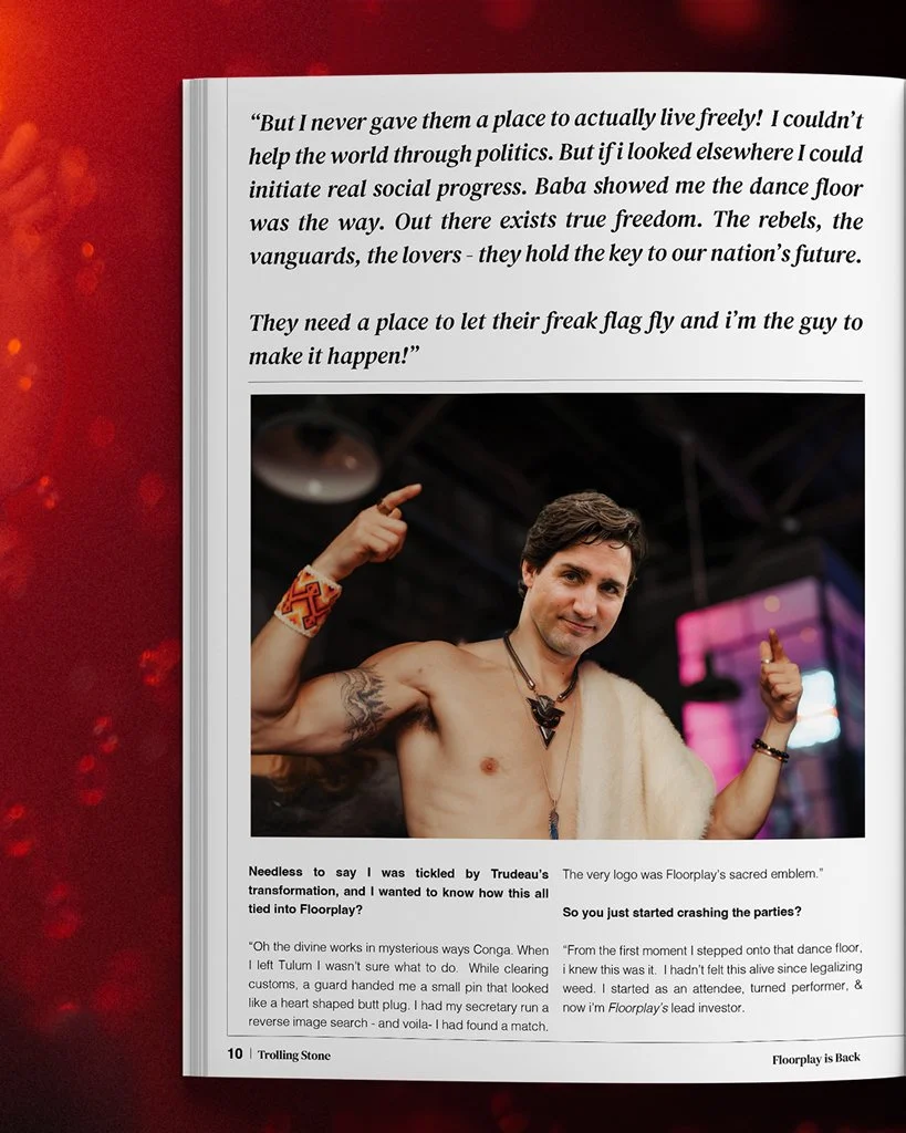 A shirtless man with tattoos on his arm and a colorful bracelet, wearing necklaces and a white shawl, smiling and pointing to his head with both hands in an indoor setting with colorful lighting.