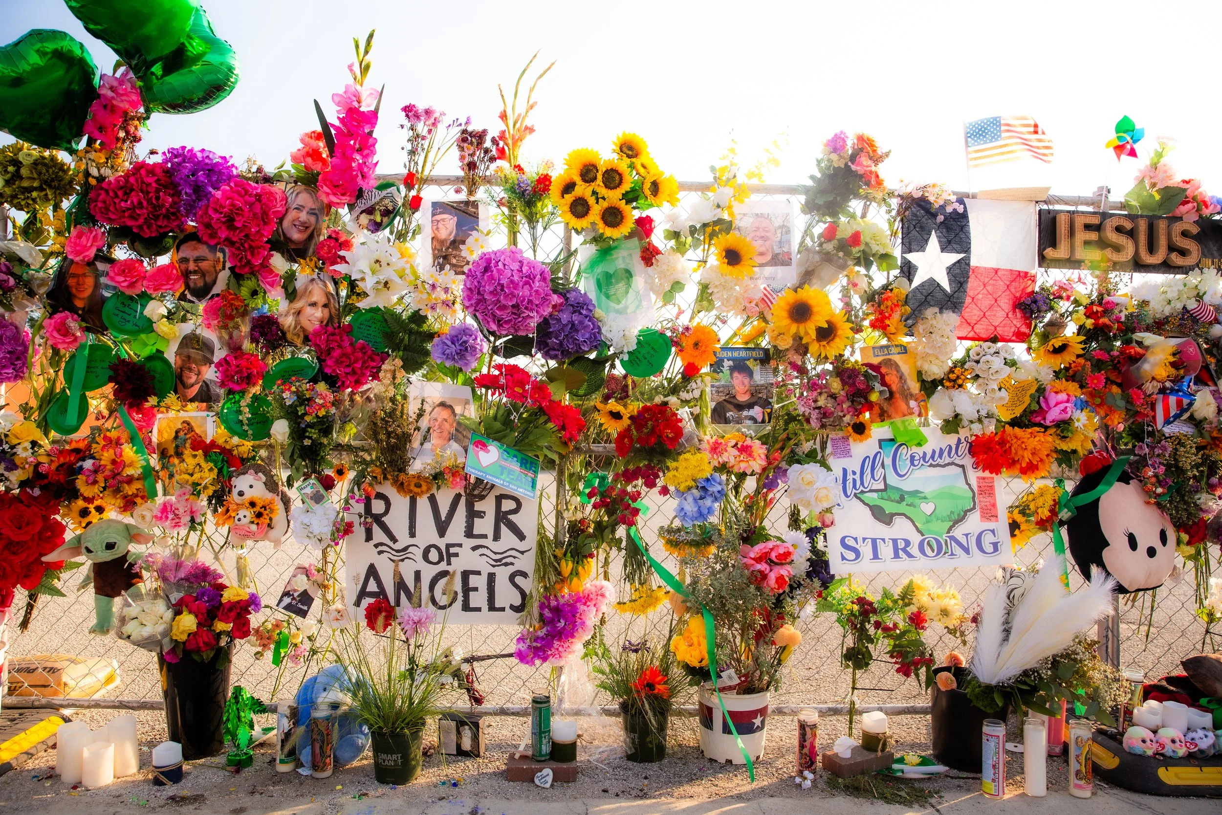 Memorial outside with colorful flowers, photos, signs, and stuffed animals for shooting victims.