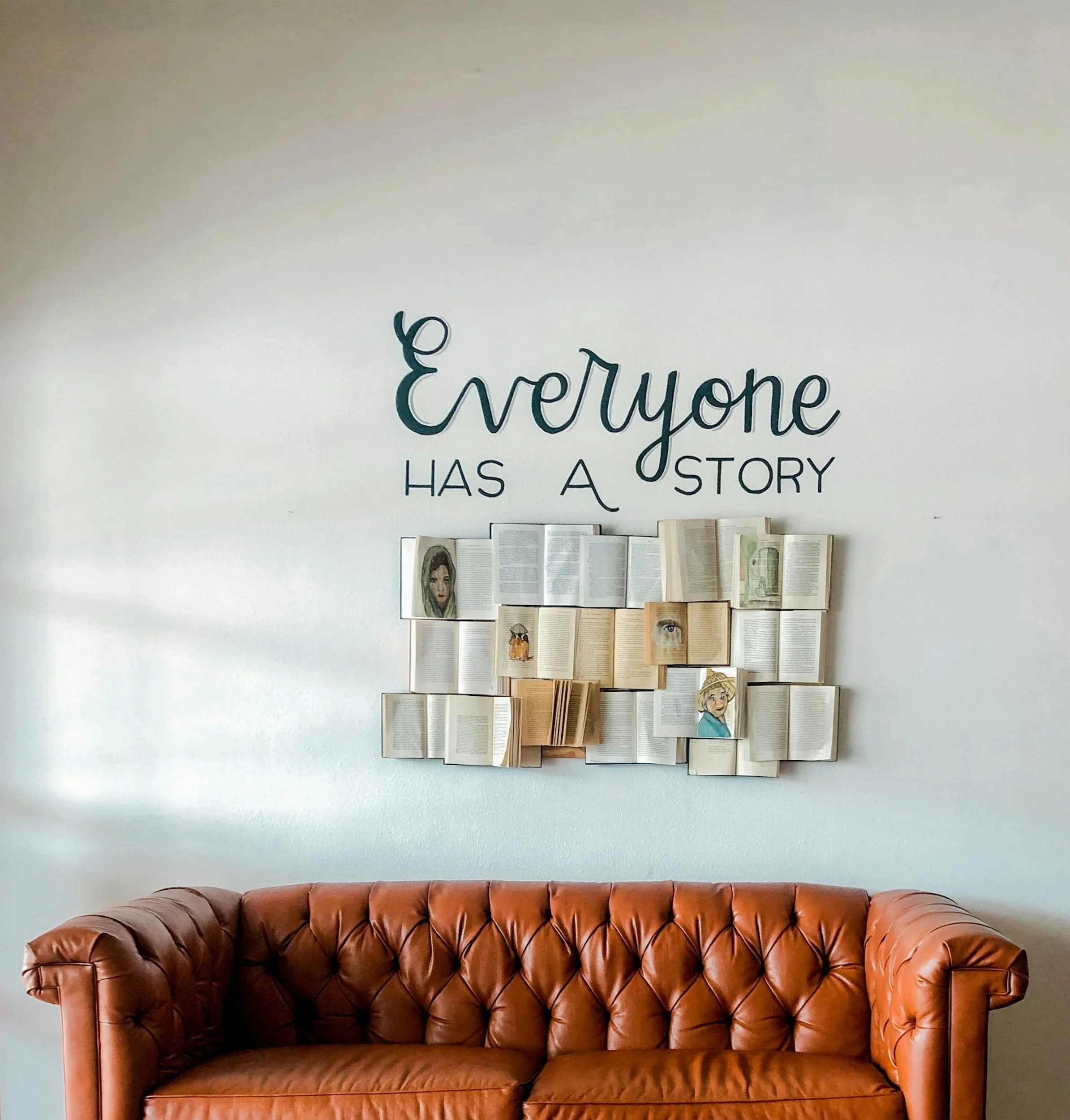 Wall art reading ‘Everyone has a story’ above a couch, emphasizing the importance of understanding each patient’s personal story.