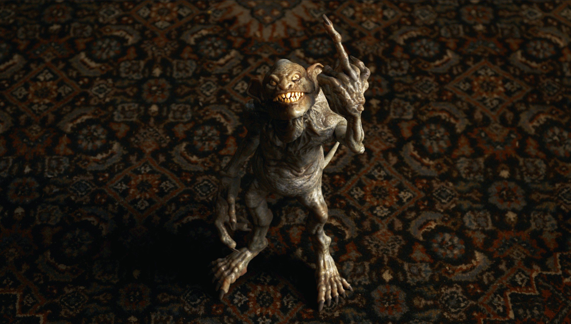 A small, goblin-like creature with tan skin, large teeth, and spiky hair standing on a patterned carpet.