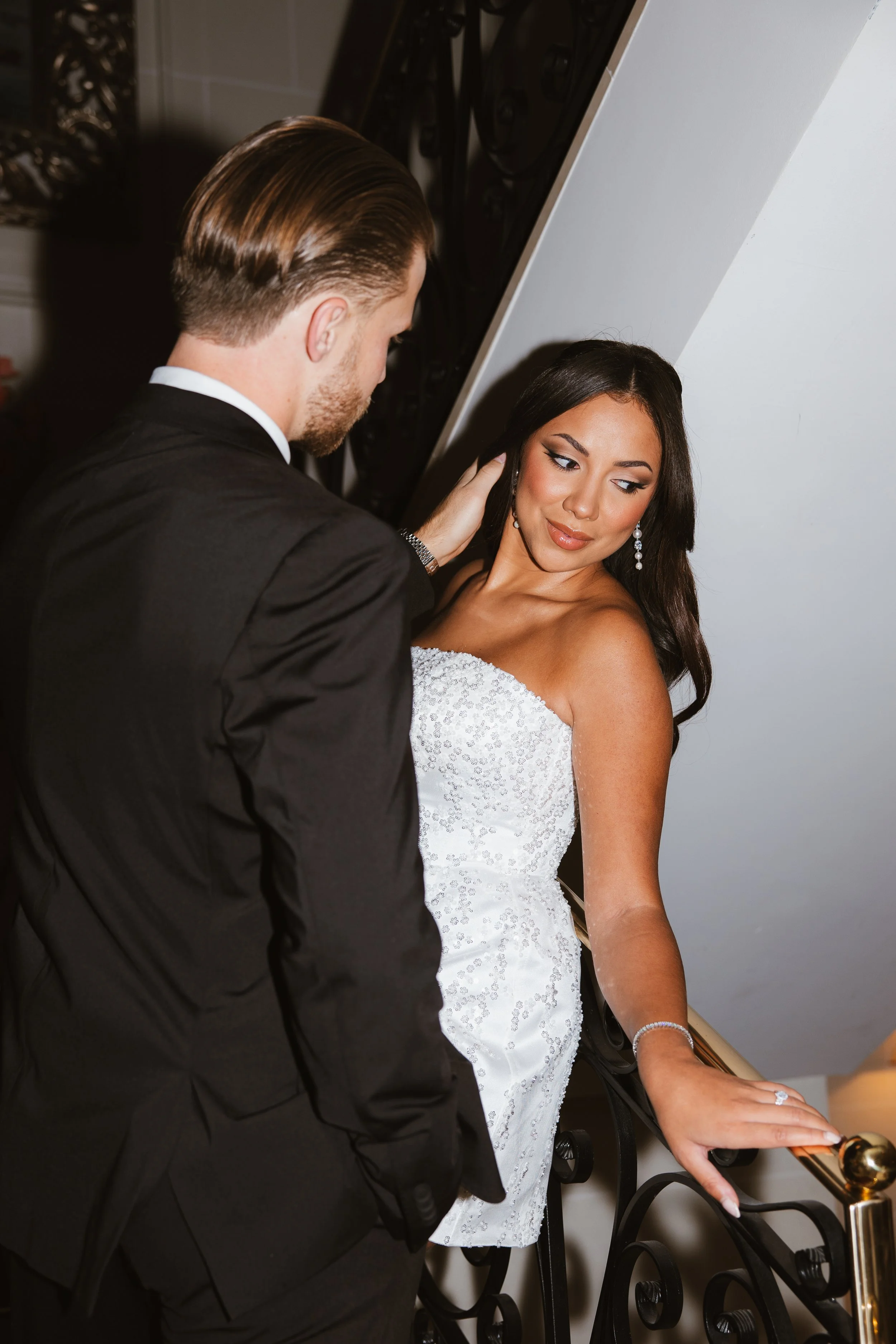 Un homme en smoking et une femme en robe de mariée posent ensemble dans une scène élégante.
