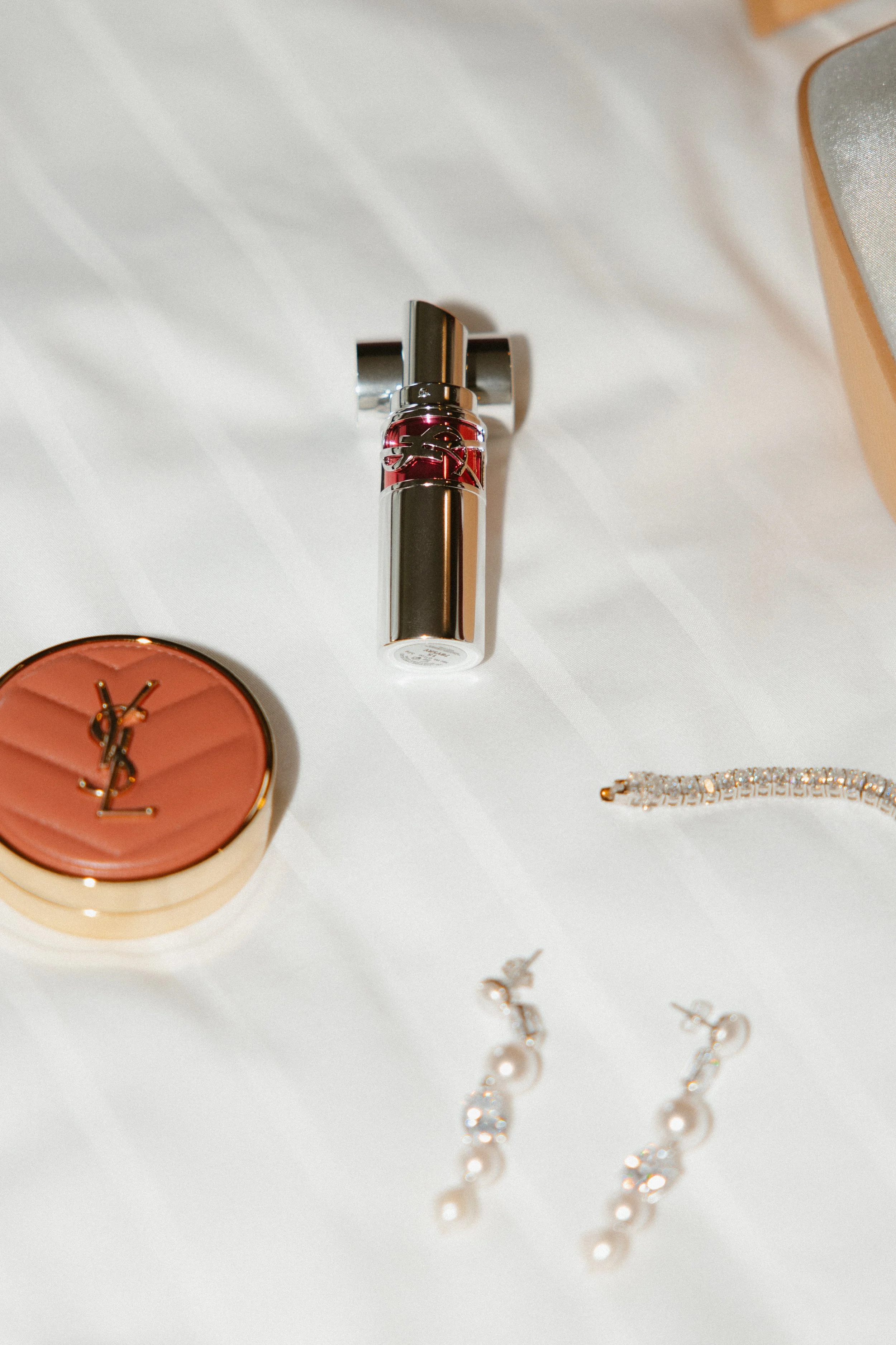 Vente de produits de maquillage et de bijoux de luxe sur une surface blanche.